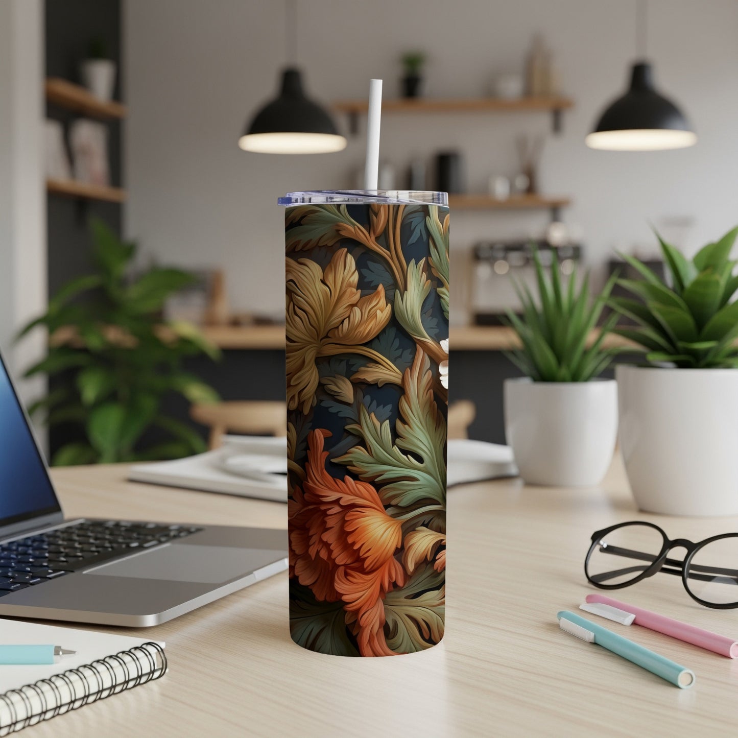 Tall floral tumbler with orange and green patterns on a desk.