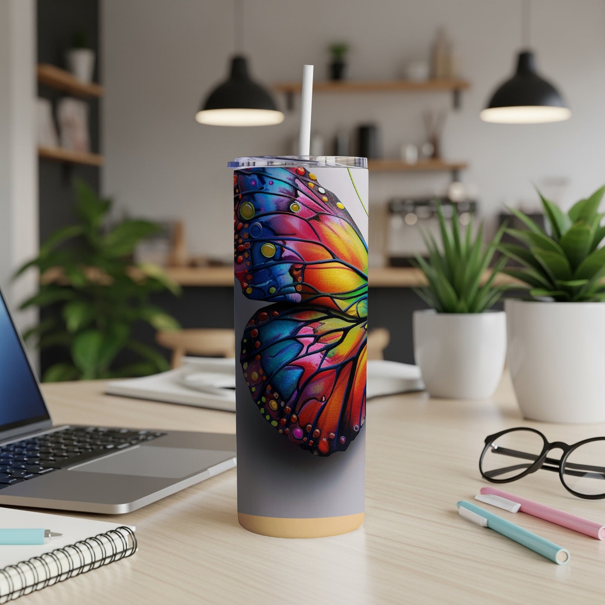 Tumbler with colorful butterfly wing design and white straw on desk.