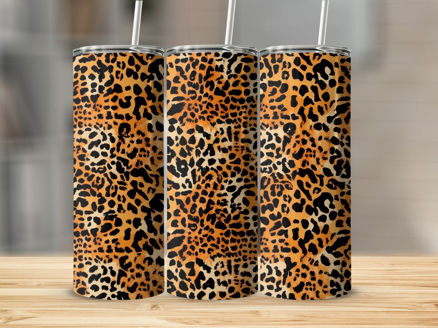 Three tumblers with leopard print patterns on a wooden surface.