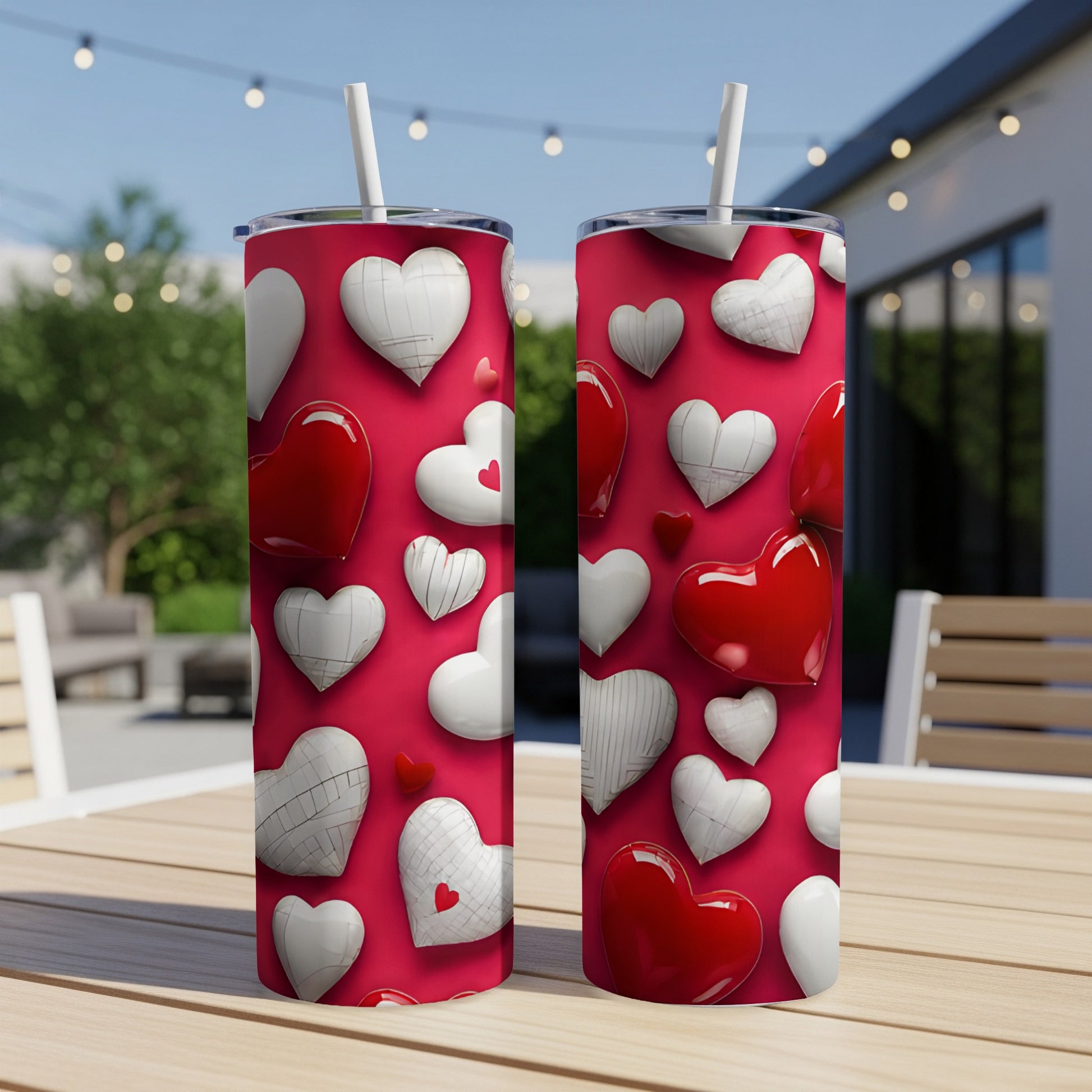 Two red tumblers with a white and red heart pattern on a patio table.