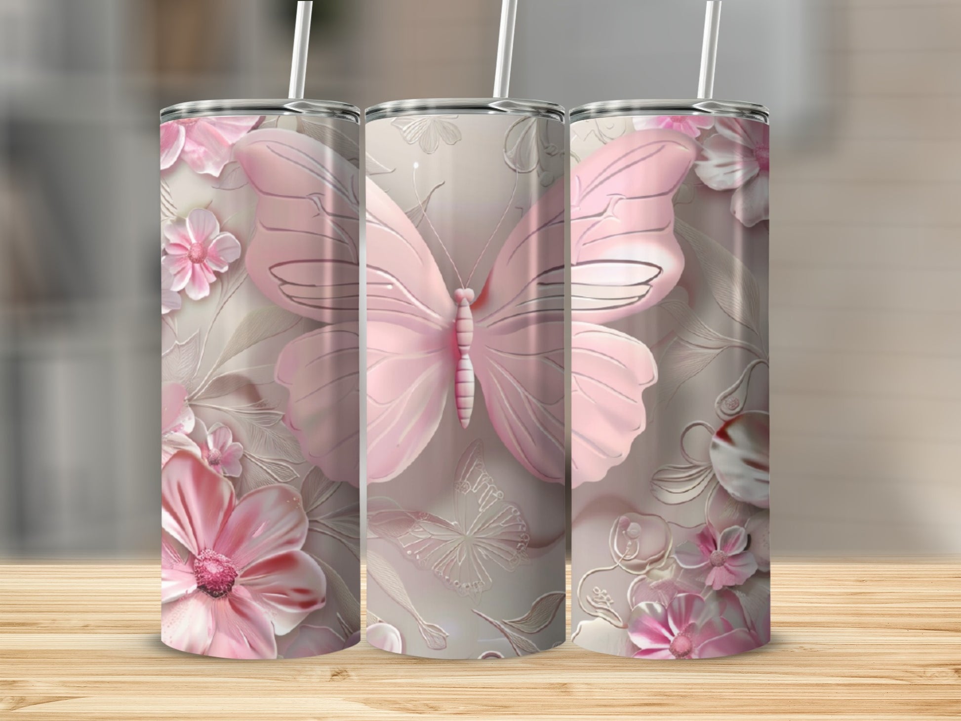 Pink butterfly and floral pattern on three stainless steel tumblers.