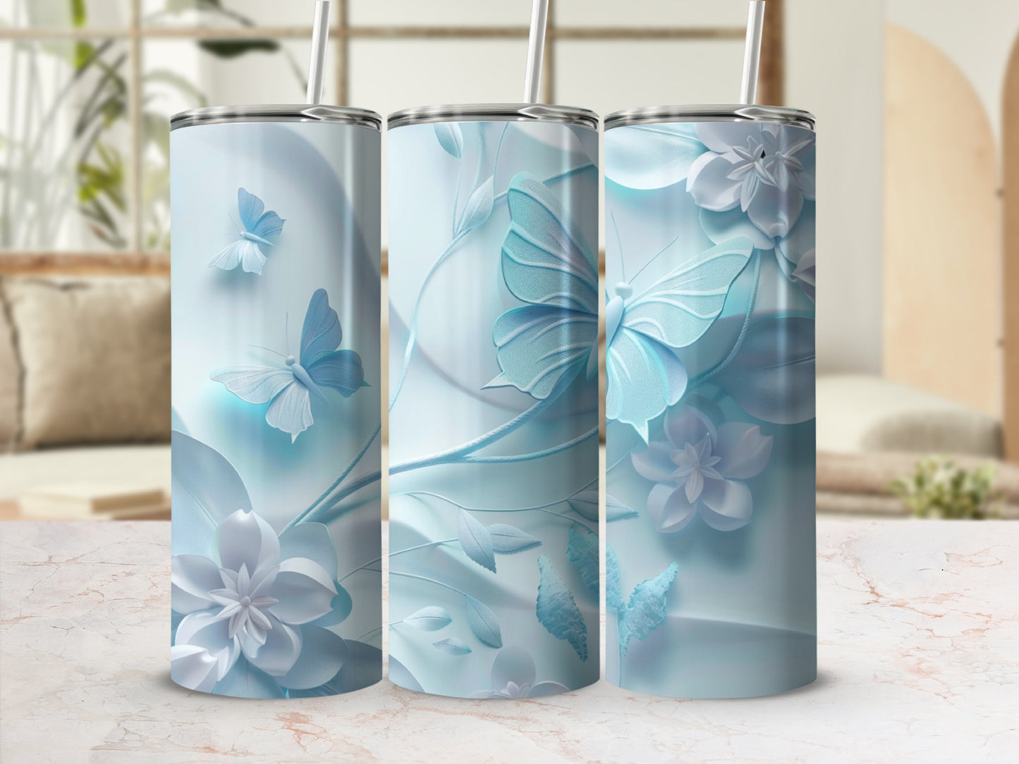 Three pastel blue butterfly and floral pattern tumblers with straws.
