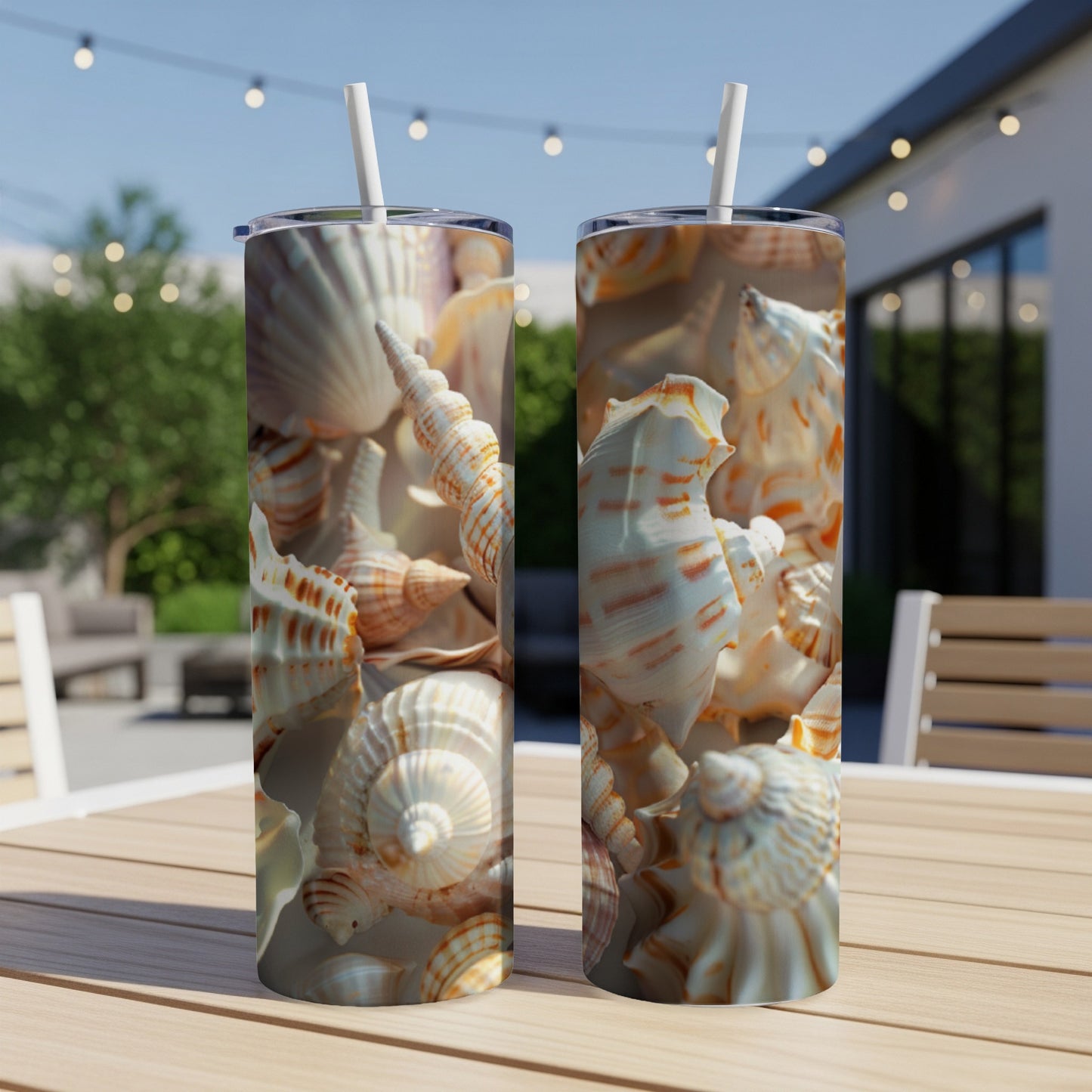 Two tall tumblers with a seashell pattern sit on a table outdoors.