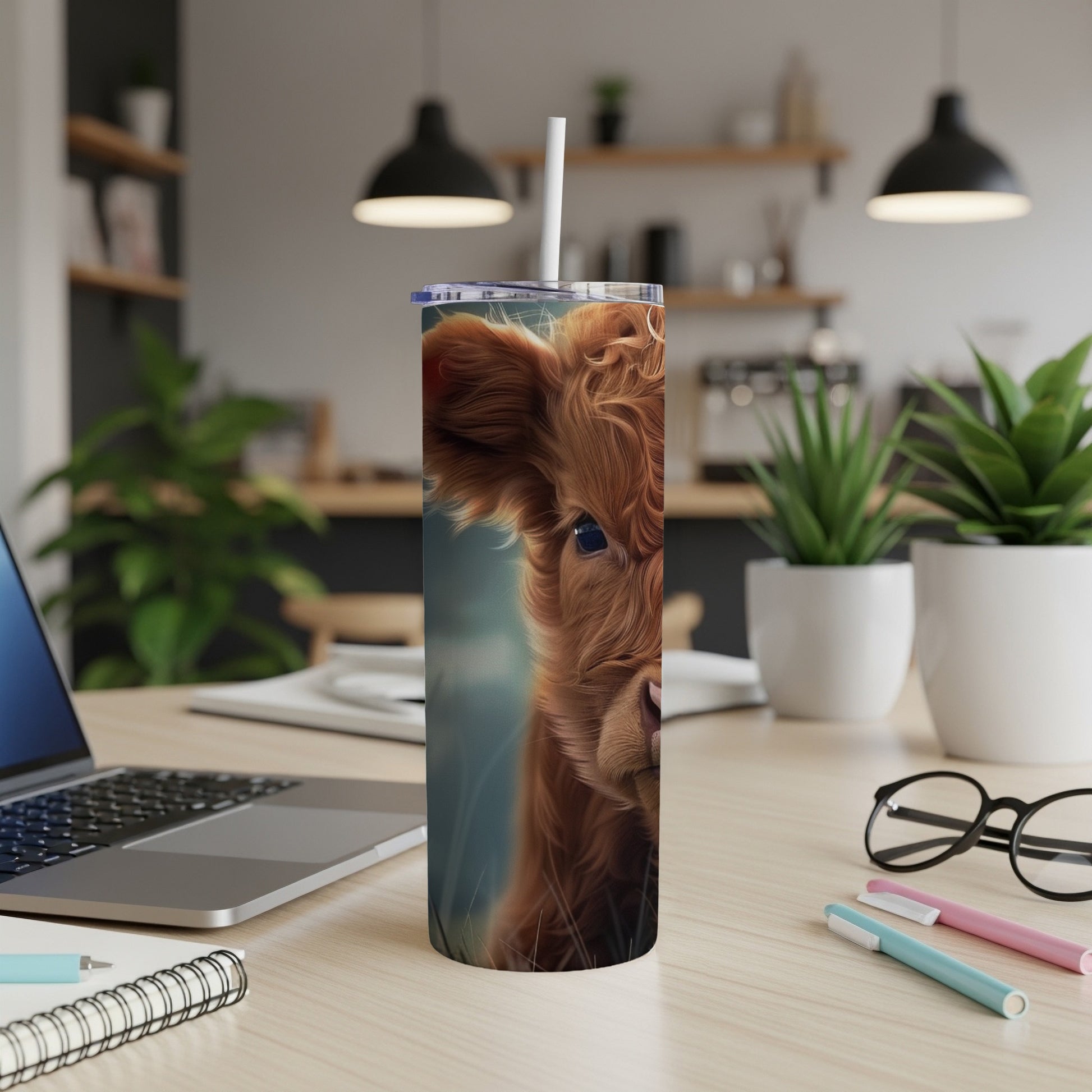 Fluffy Highland cow face on a tumbler with a straw and office desk background.