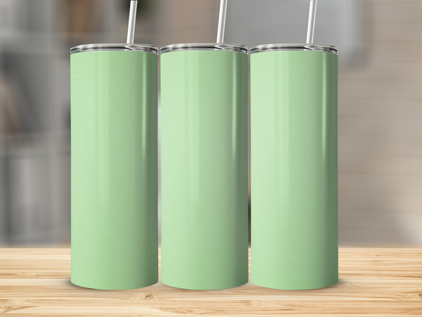 Three mint green tumblers with white straws stand on a wooden surface.