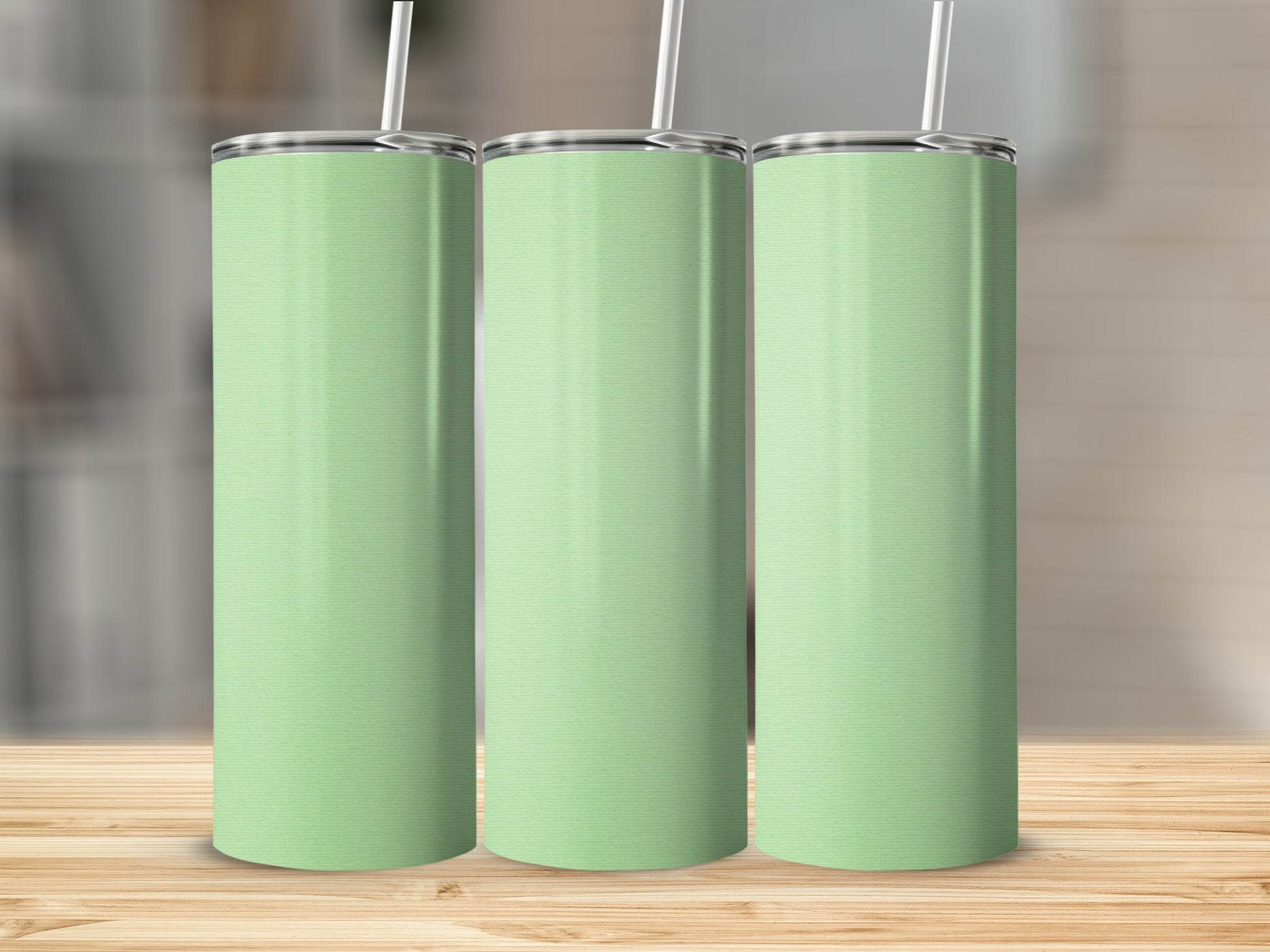 Three mint green tumblers with white straws stand on a wooden surface.