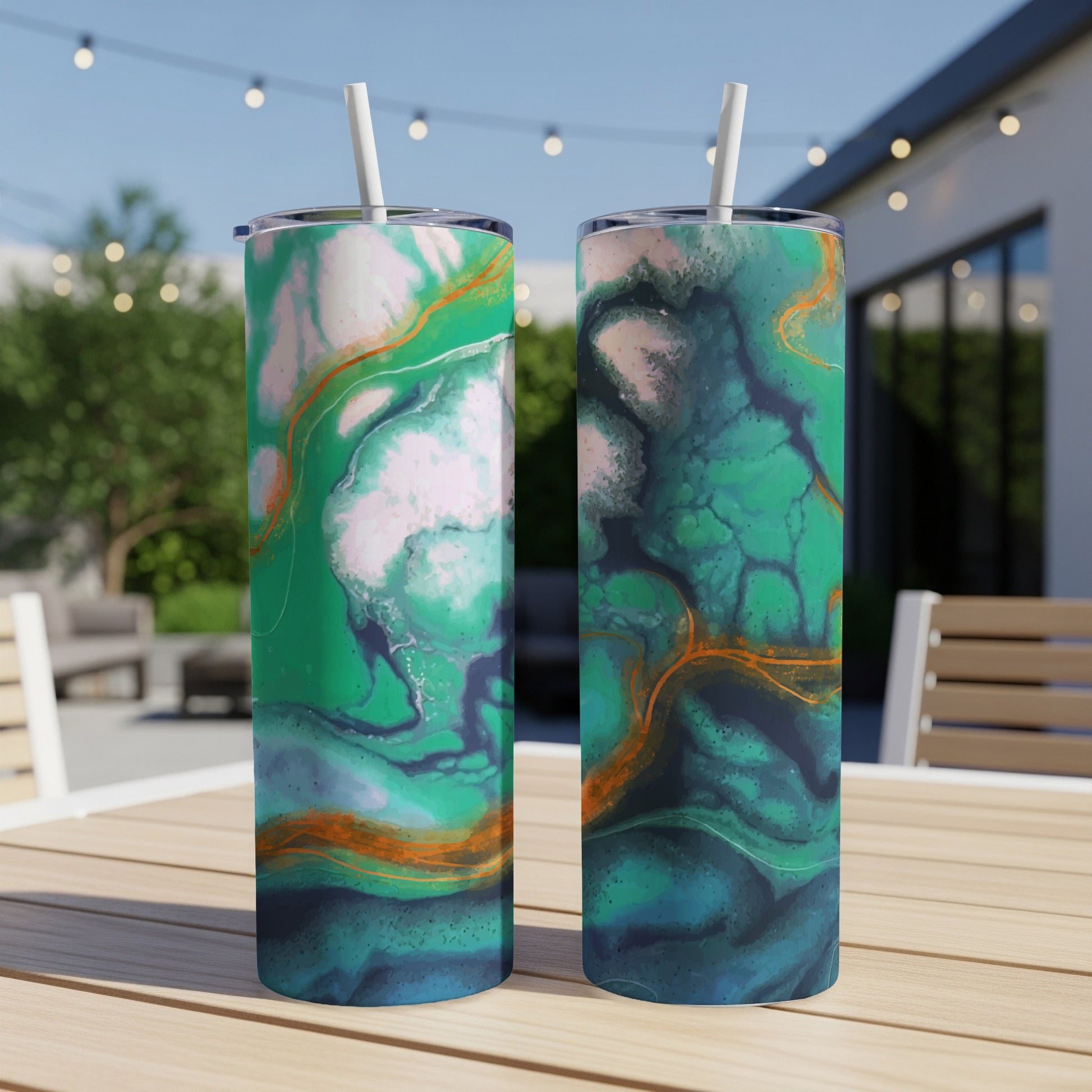 Two tumblers with abstract green and blue marble designs and orange accents are displayed outdoors.