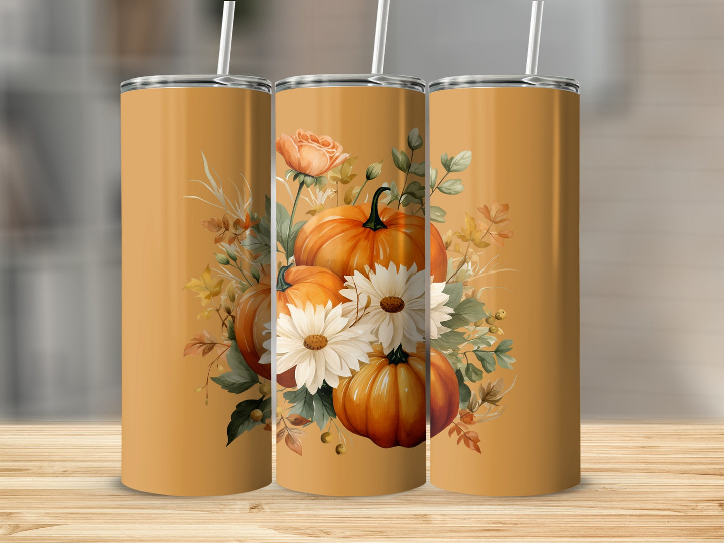 Three orange tumblers with pumpkins, roses, and daisies on a wooden surface.