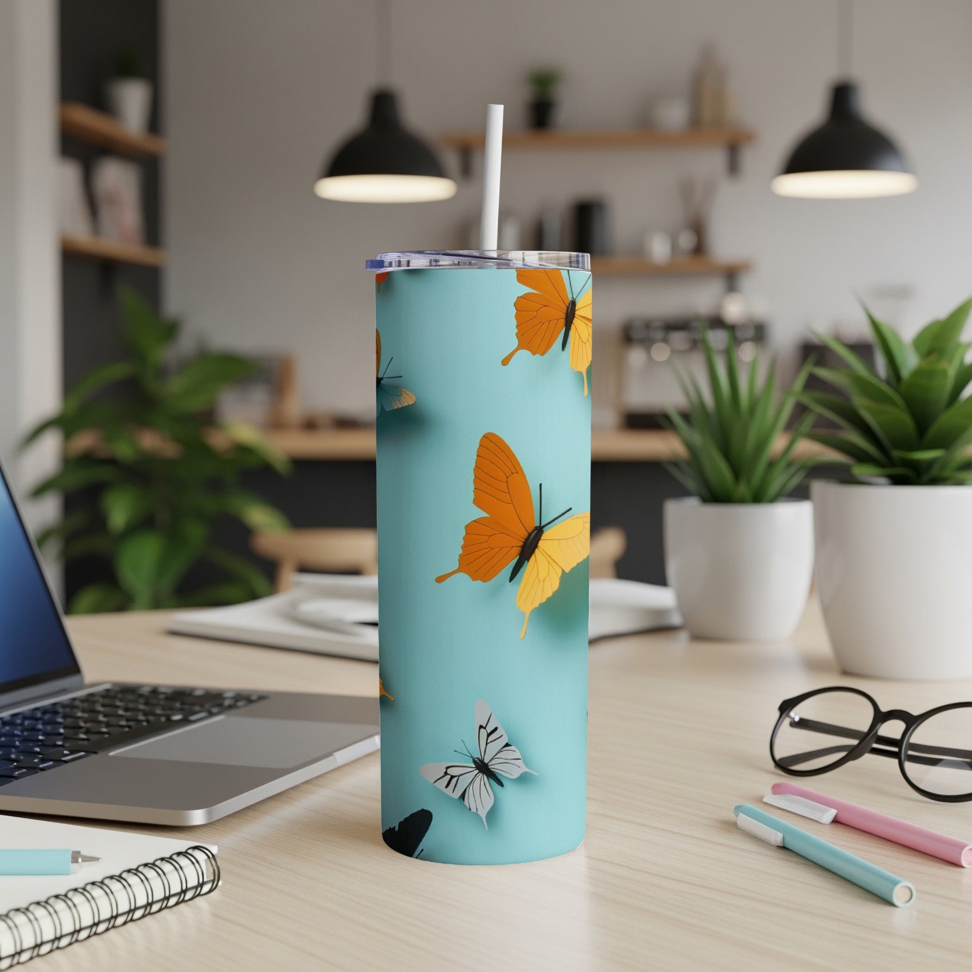 Light blue tumbler with orange and black butterflies, white straw, on desk.