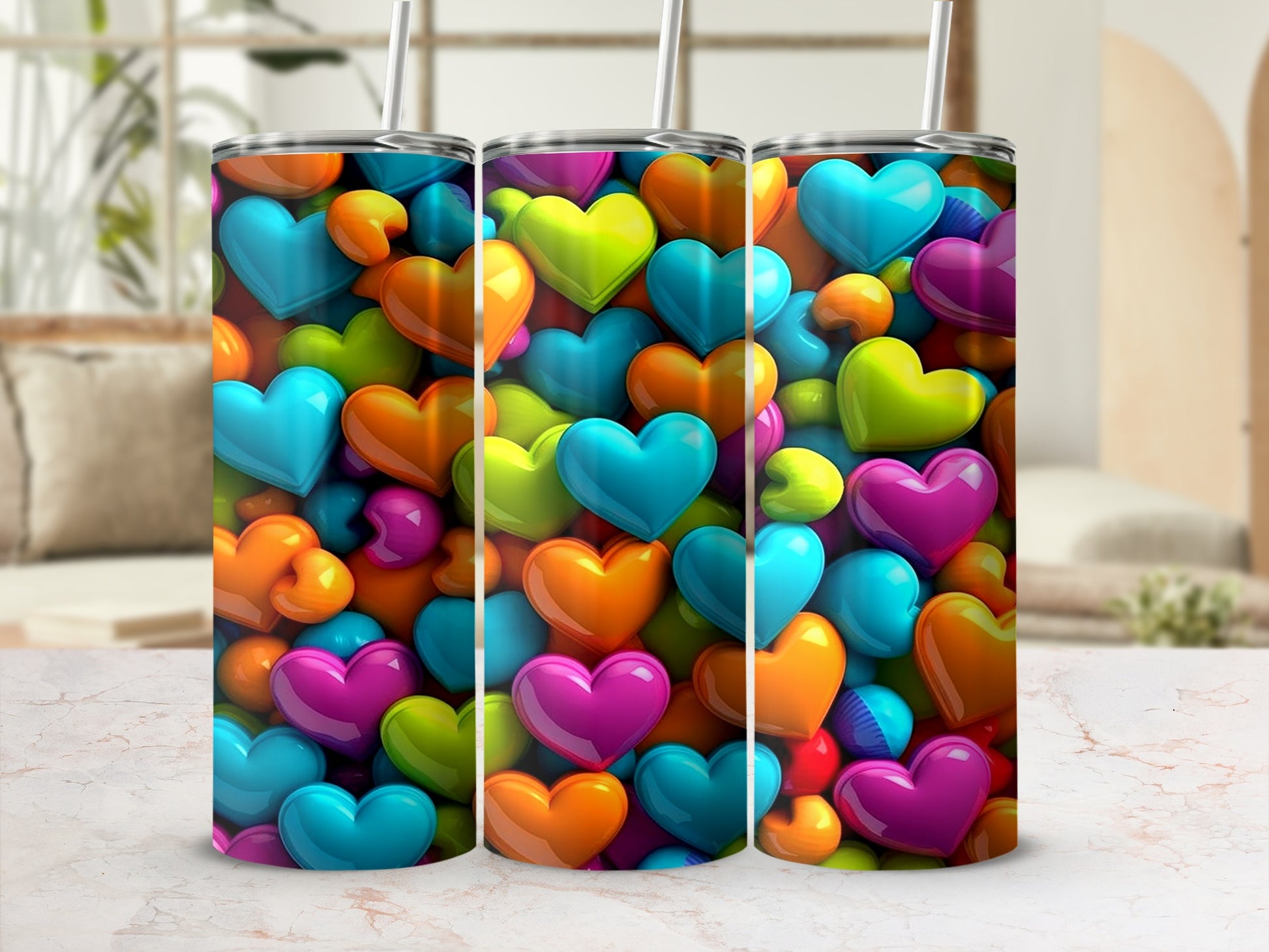 Three colorful heart-shaped tumblers with straws, displayed on a marbled surface.