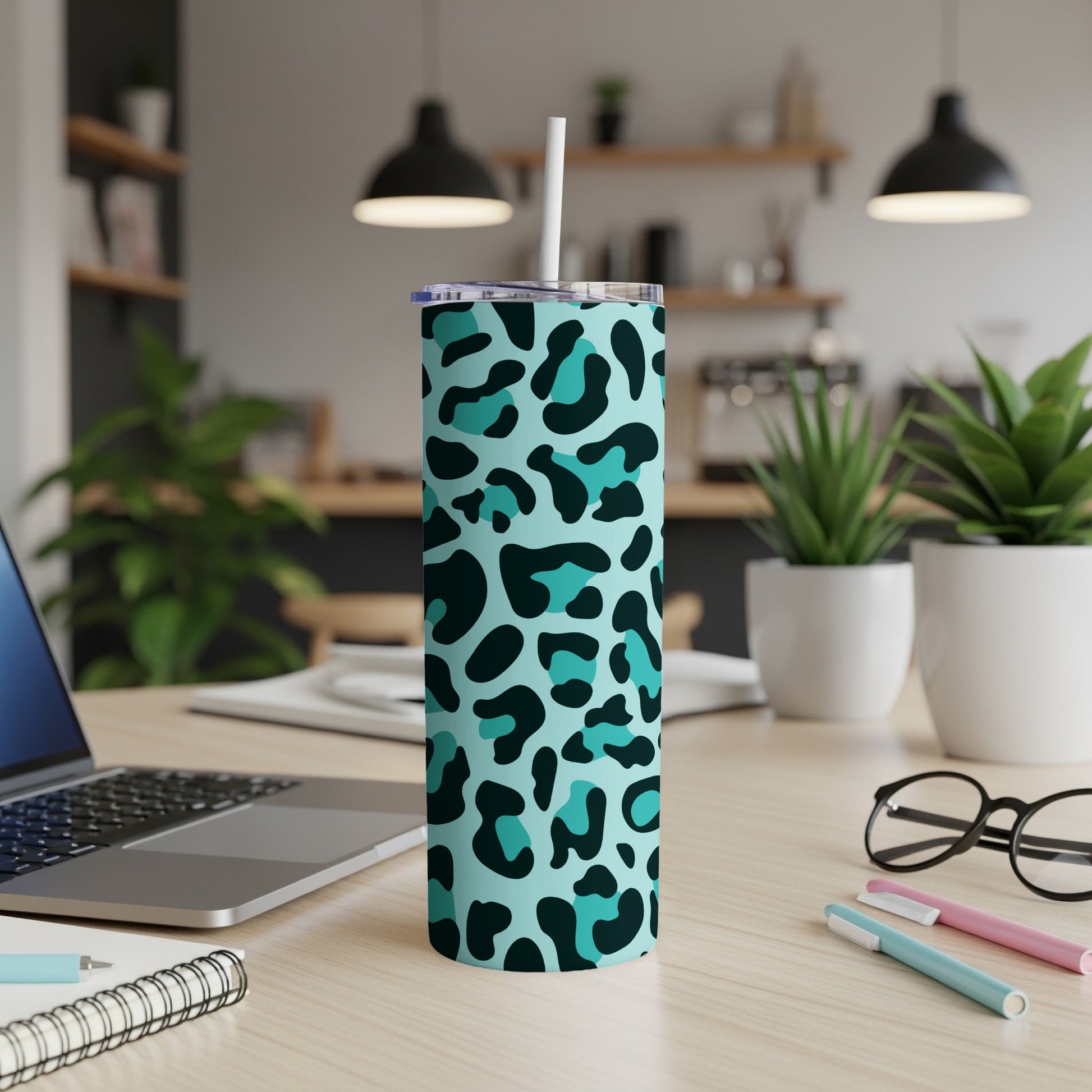 Aqua leopard print tumbler with white straw on a desk.