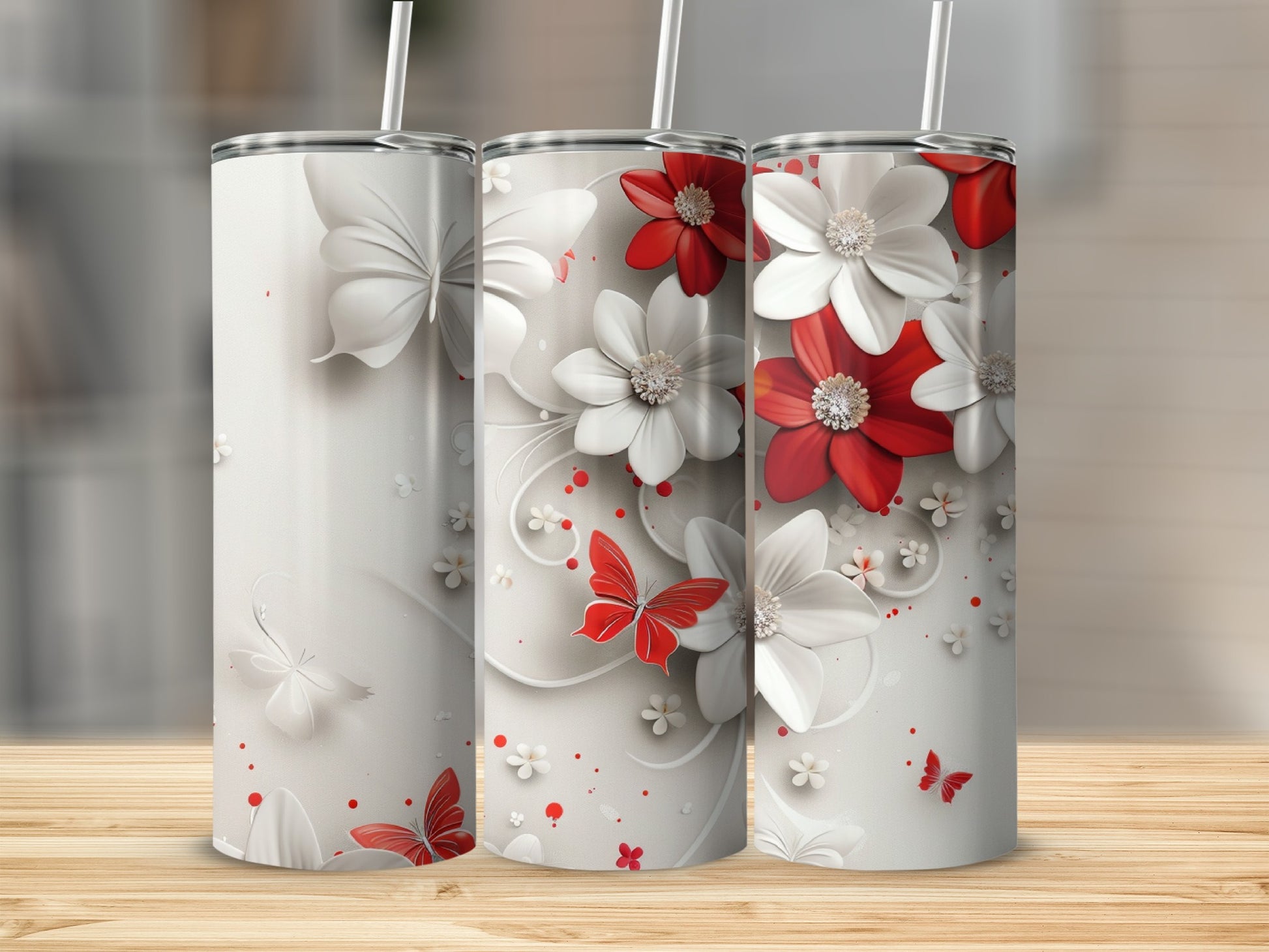 Three stainless steel tumblers with white and red flowers and butterflies.