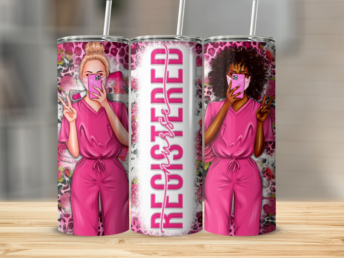 Two nurses in pink scrubs, one with blonde hair, one with dark curly hair, hold up a phone and peace sign.