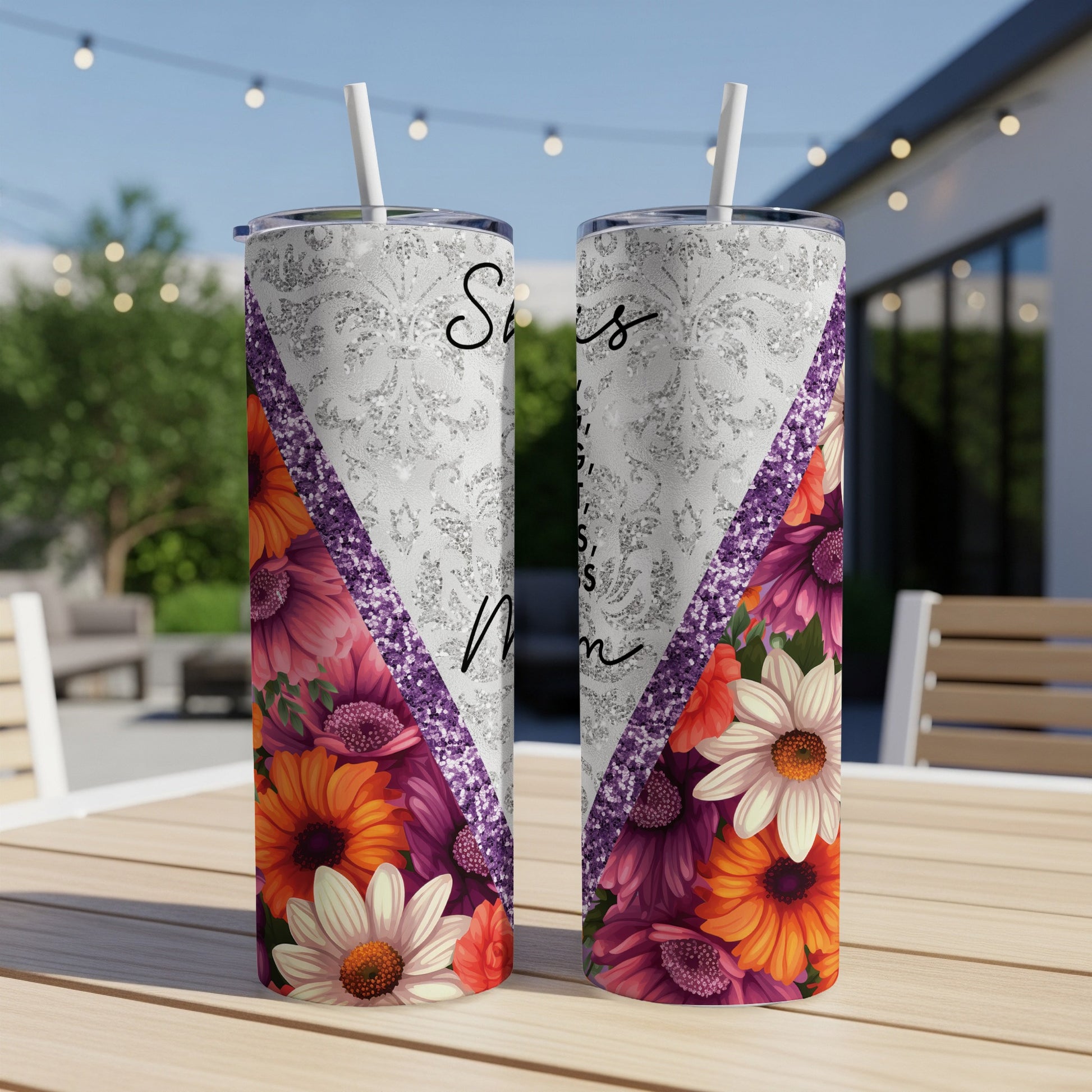 Two floral tumblers with "Sisters" text on a patio table.