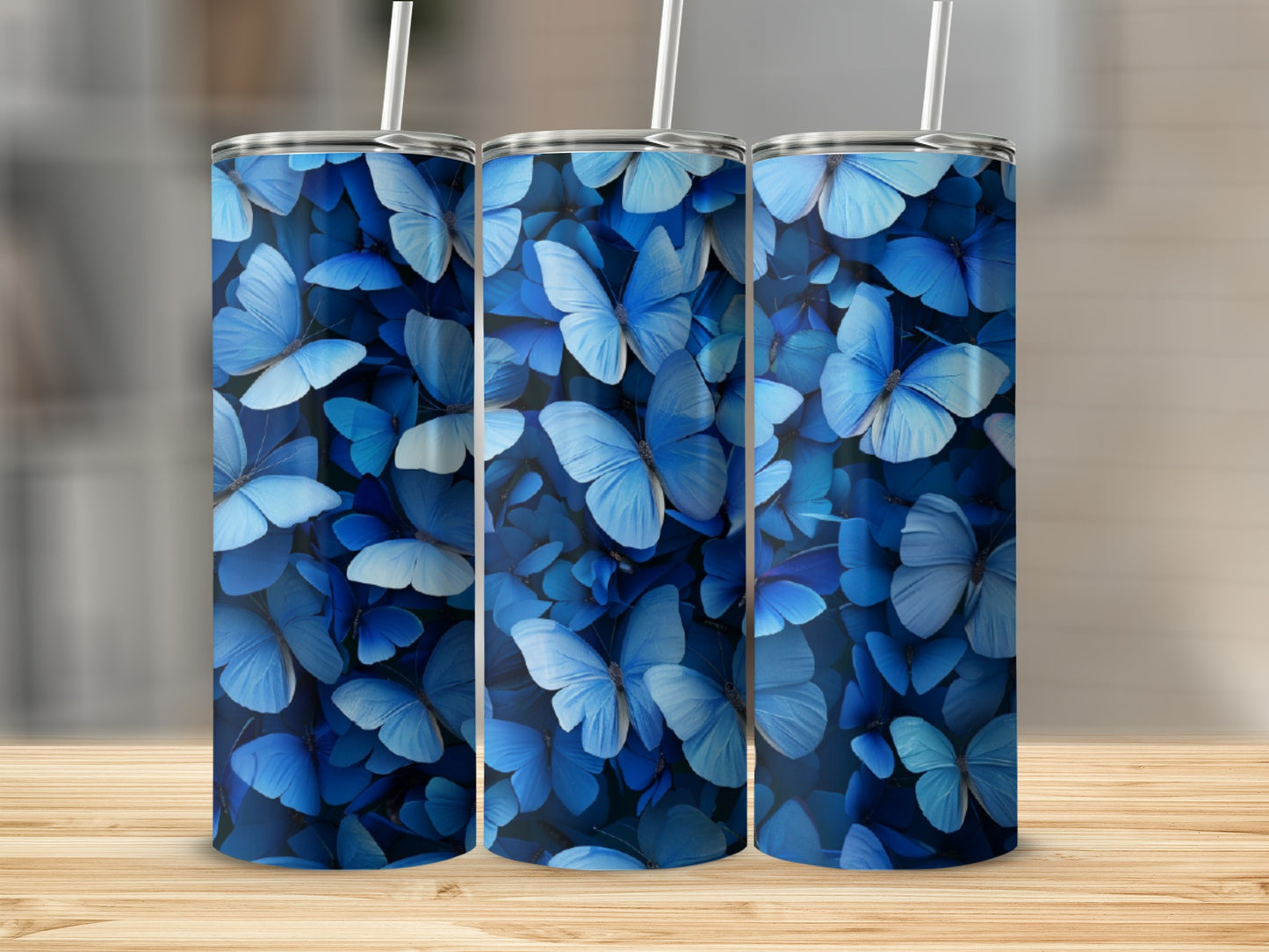 Three blue butterfly patterned tumblers on a wooden surface.