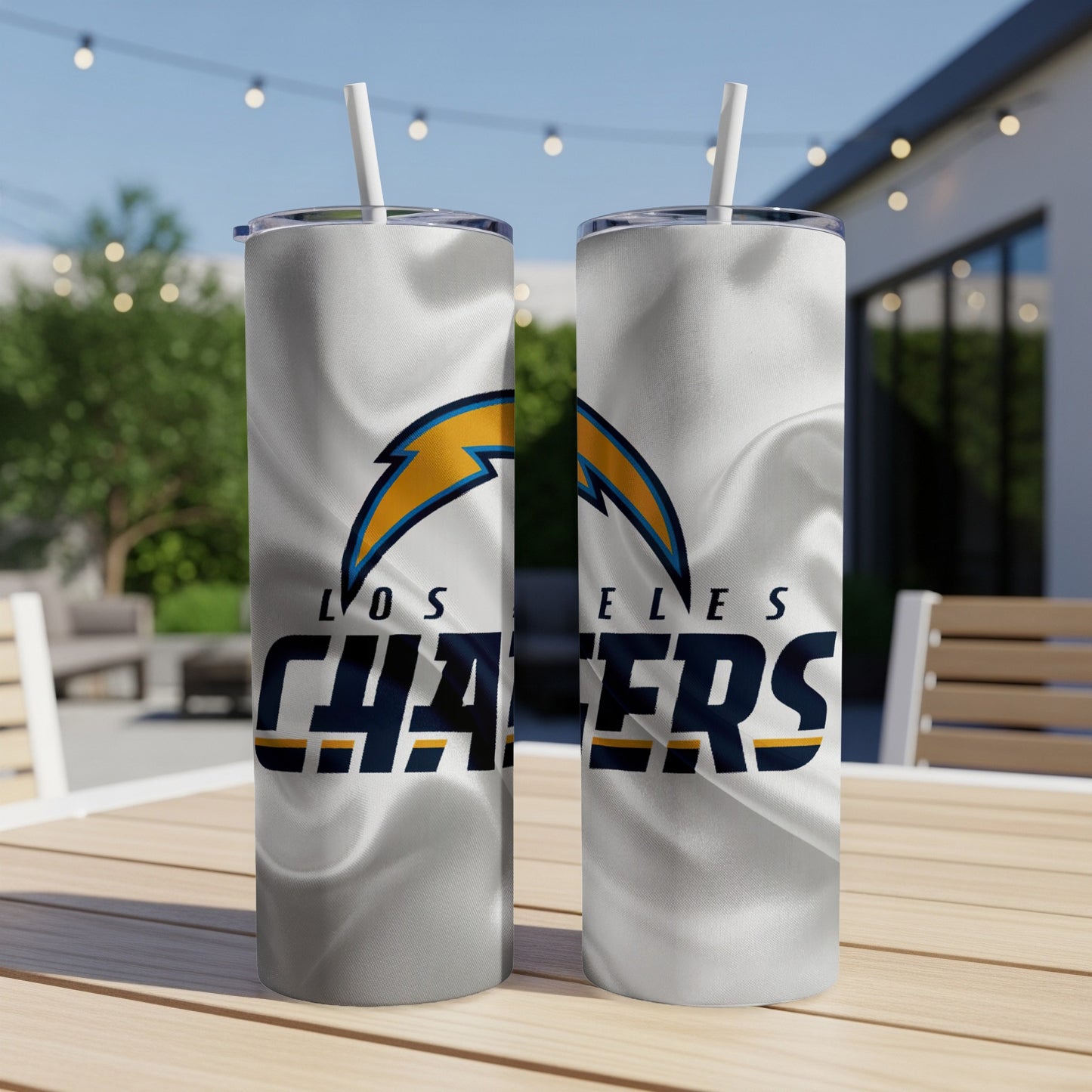 Two Los Angeles Chargers tumblers with straws on a wooden table.