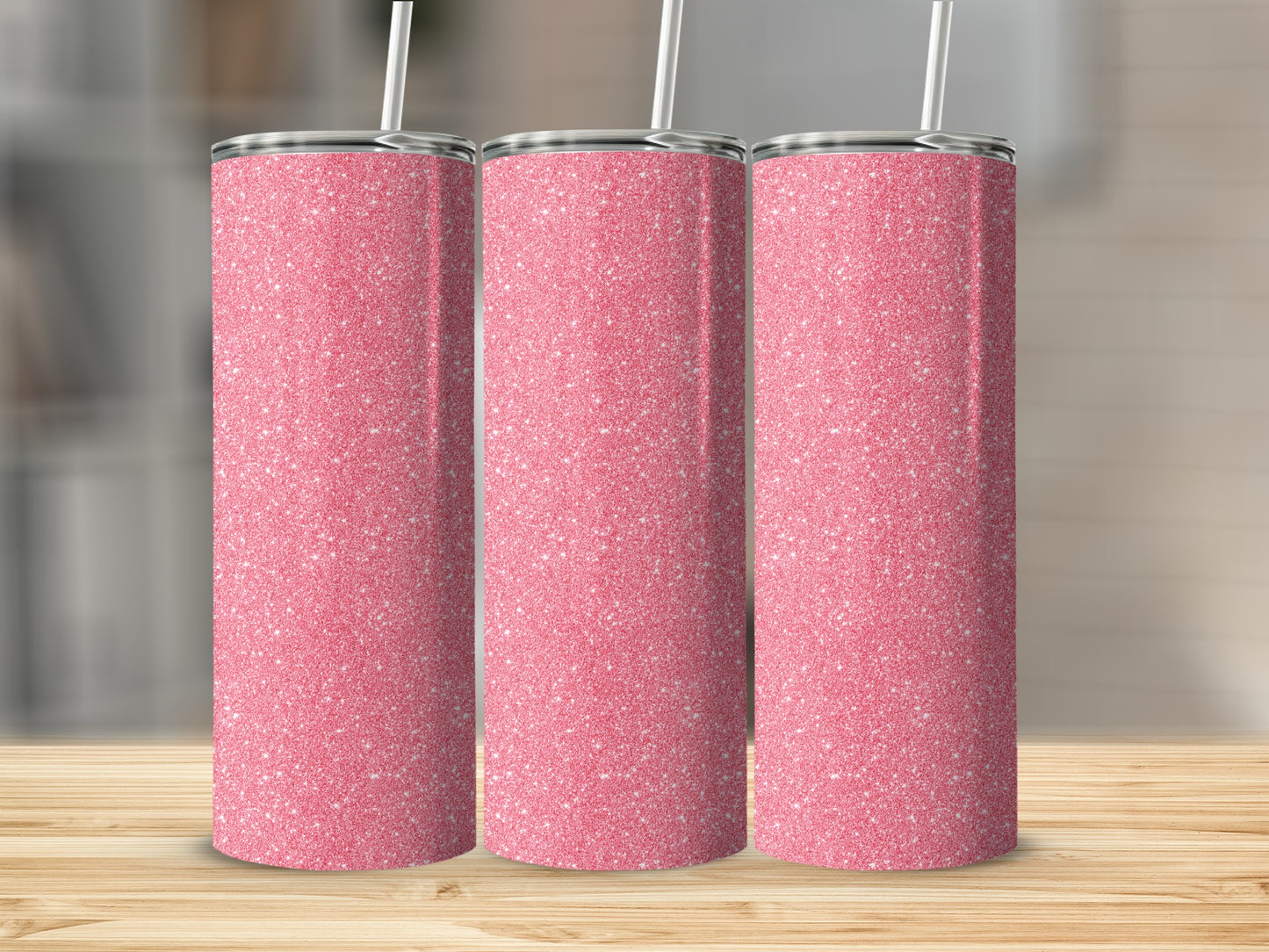 Three pink glitter tumblers with white straws on a wooden surface.