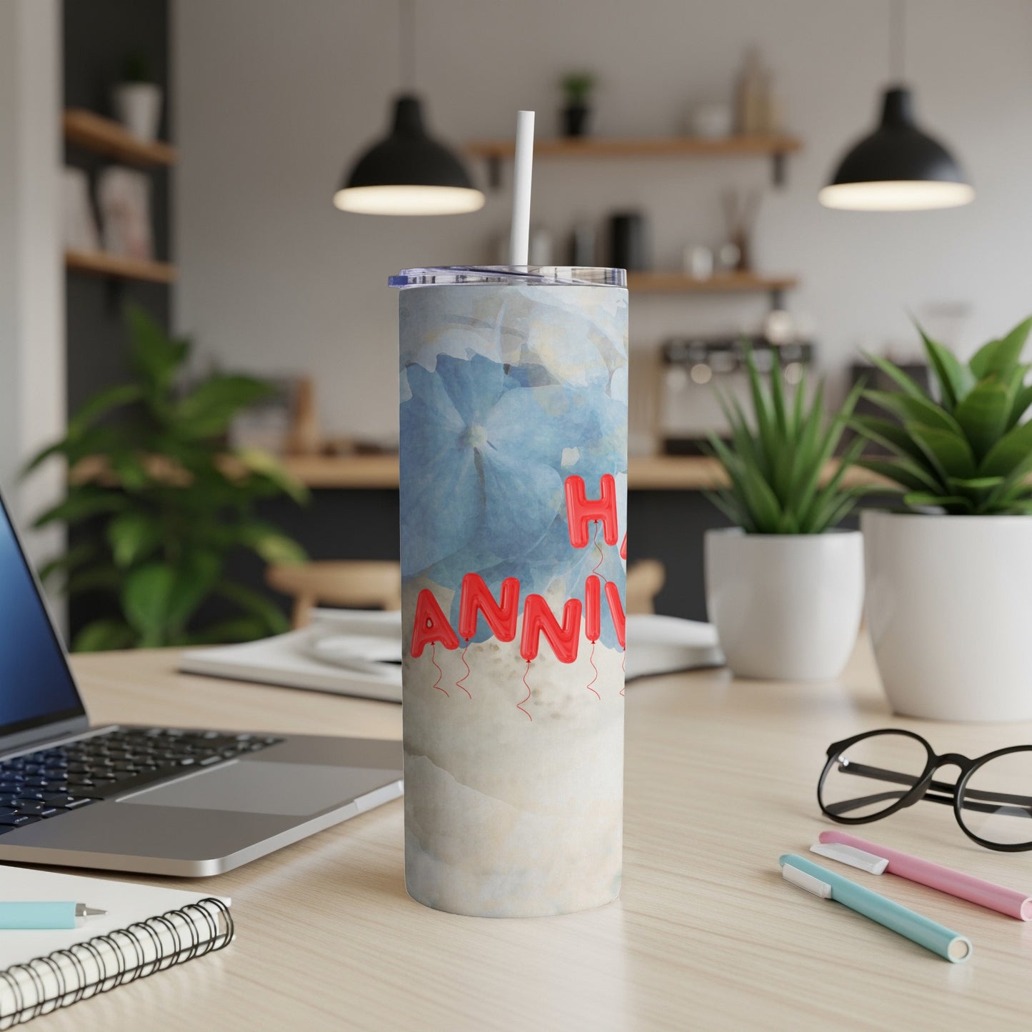 Floral tumbler with "Happy Anniversary" balloons on a desk.