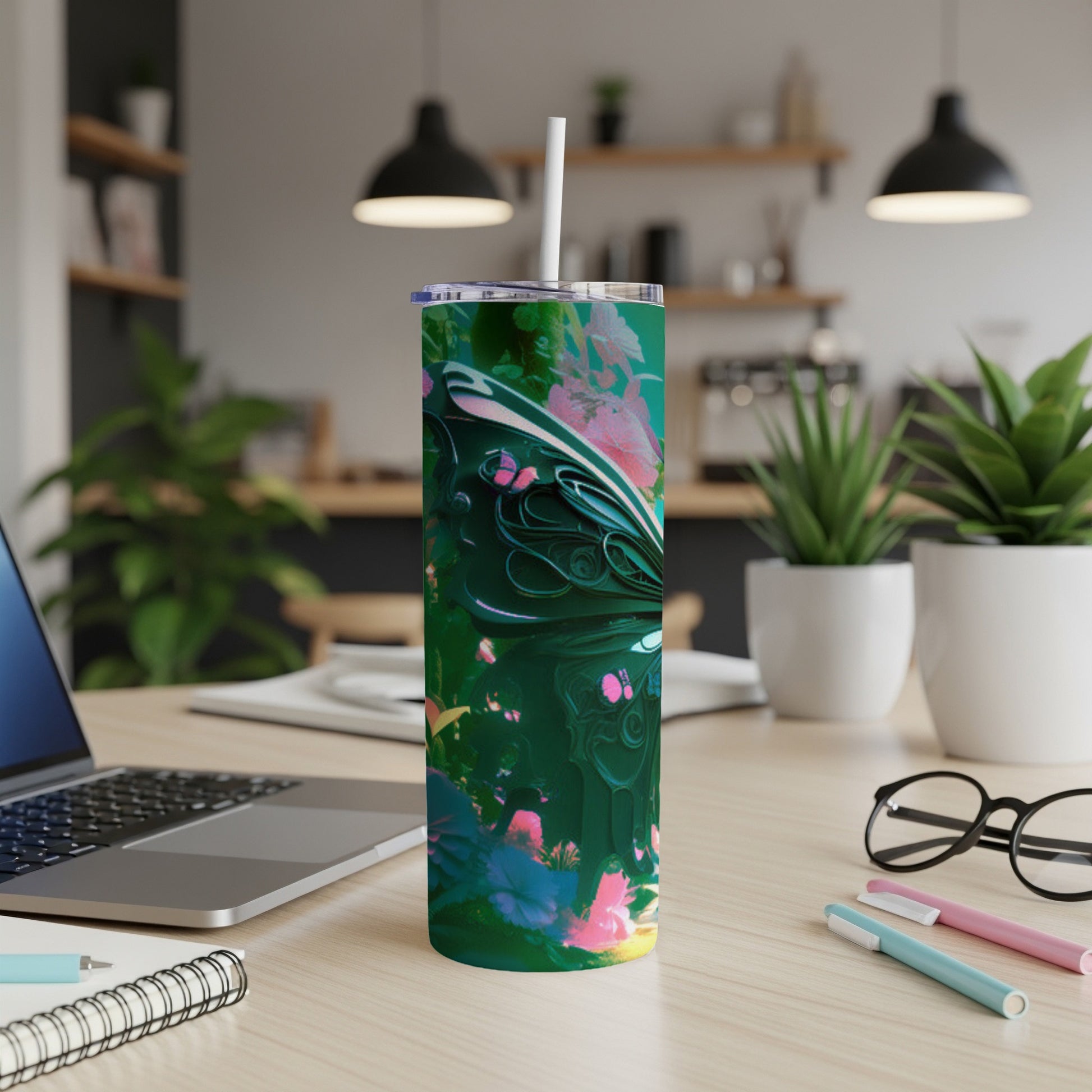 Green abstract floral tumbler with a white straw on a desk.