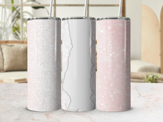 Three glitter and bokeh pattern tumblers with straws on a marble surface.