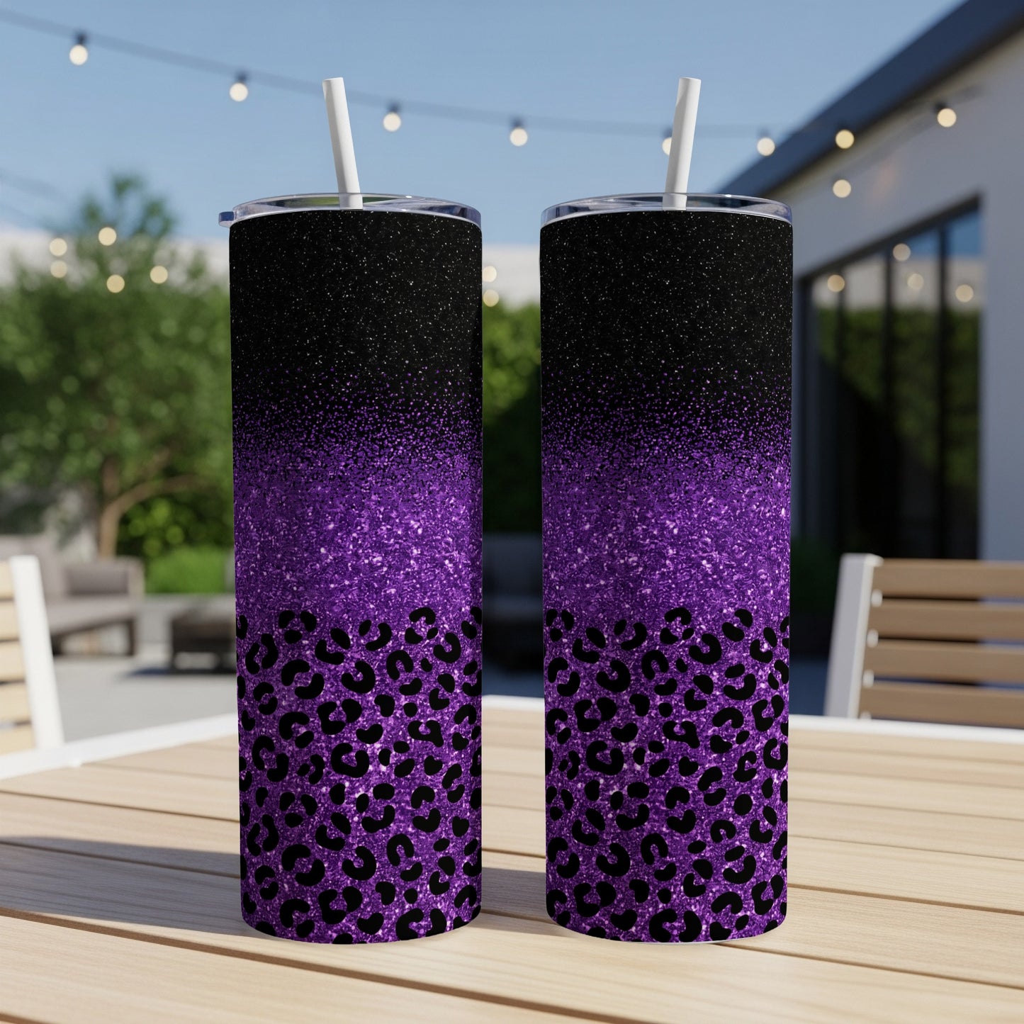 Two purple and black glitter leopard print tumblers with straws on a table.