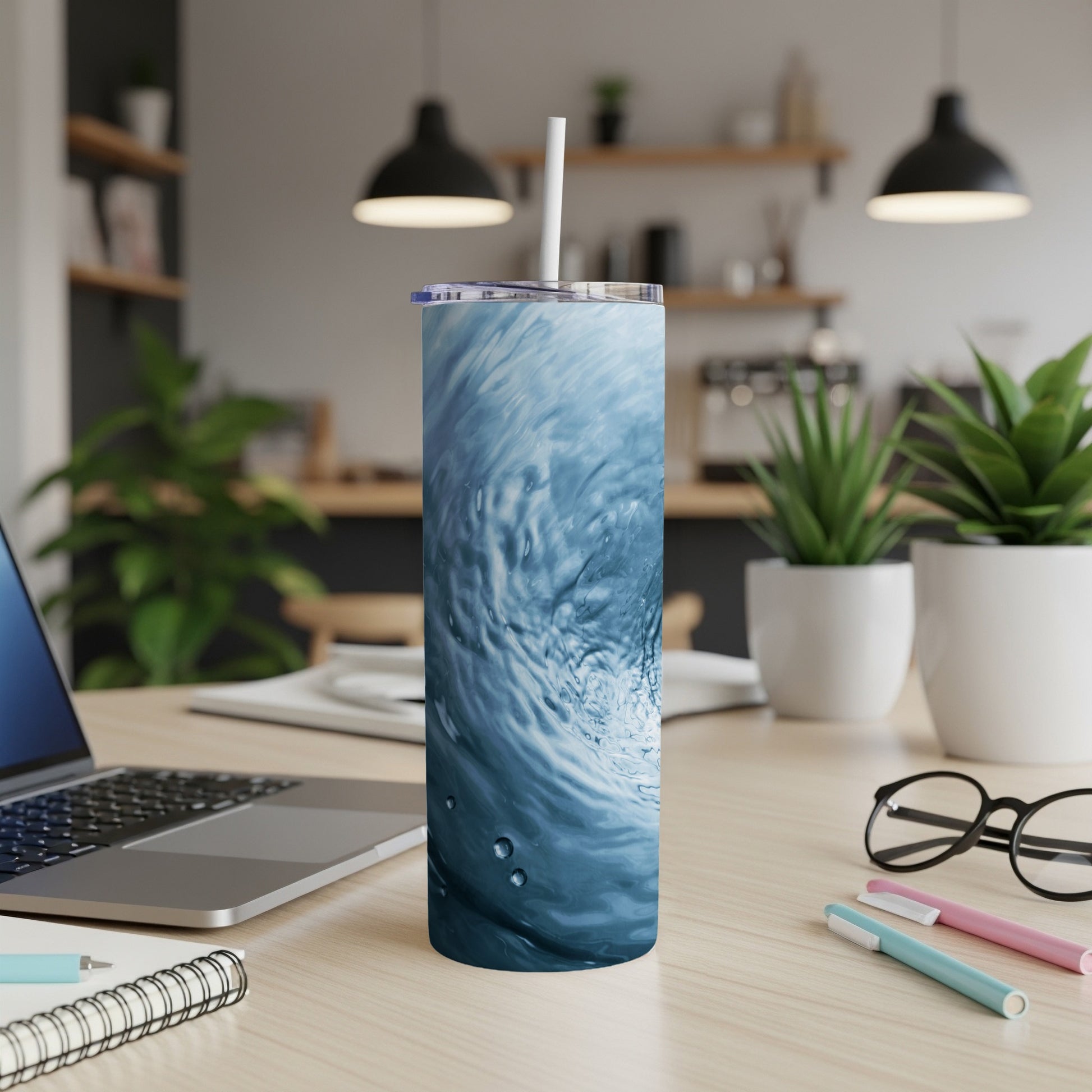 Blue wave pattern tumbler with straw on a desk.