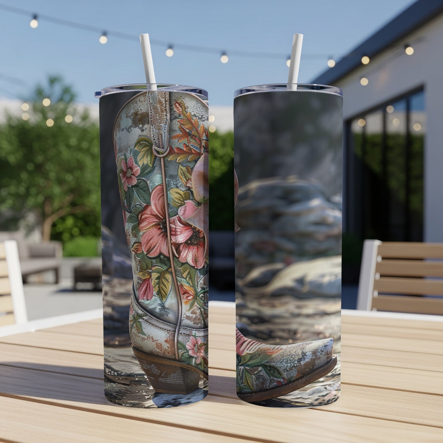 Two tumblers with floral cowboy boot design, placed on a wooden table outdoors.