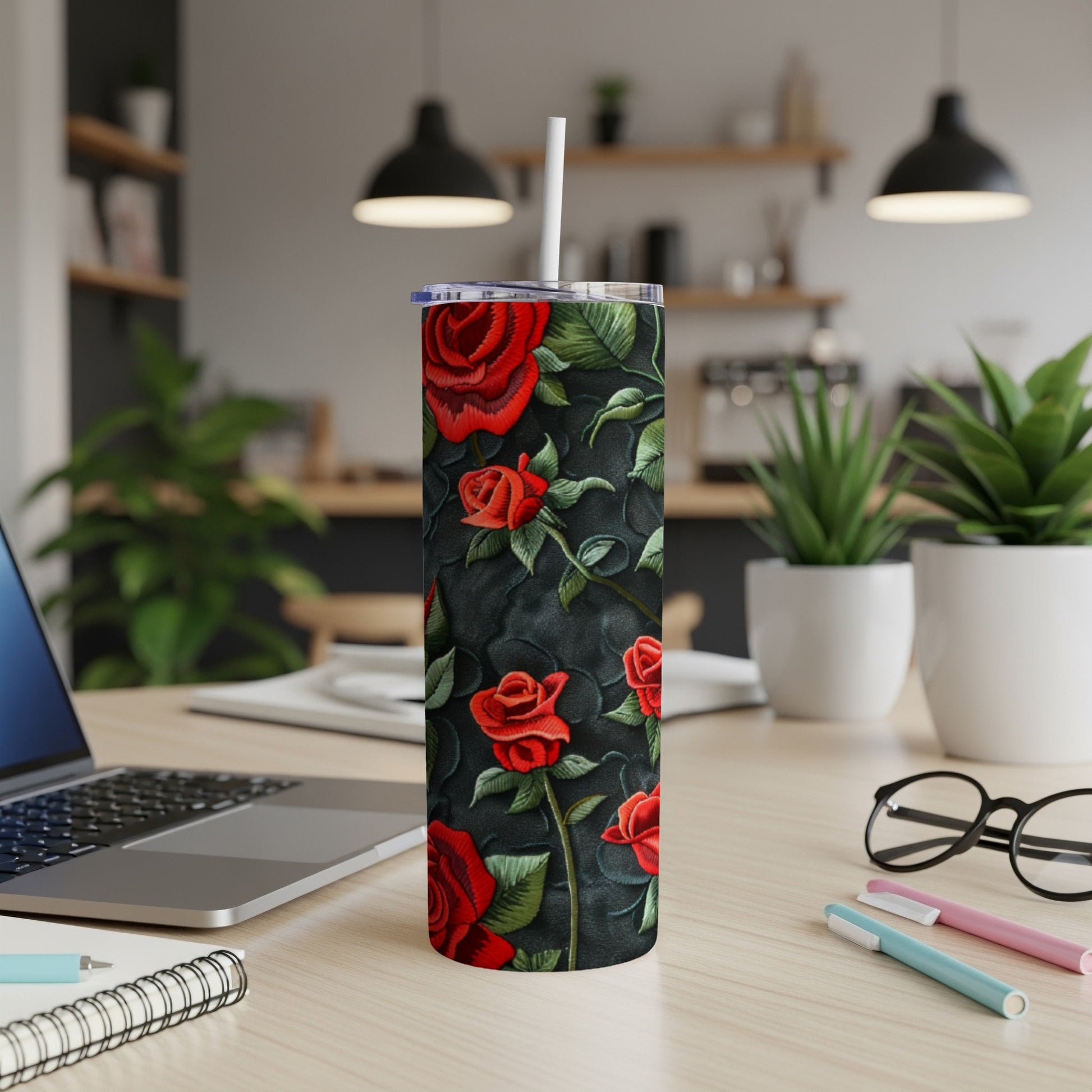 Tall tumbler with red roses and green leaves on a dark textured background.