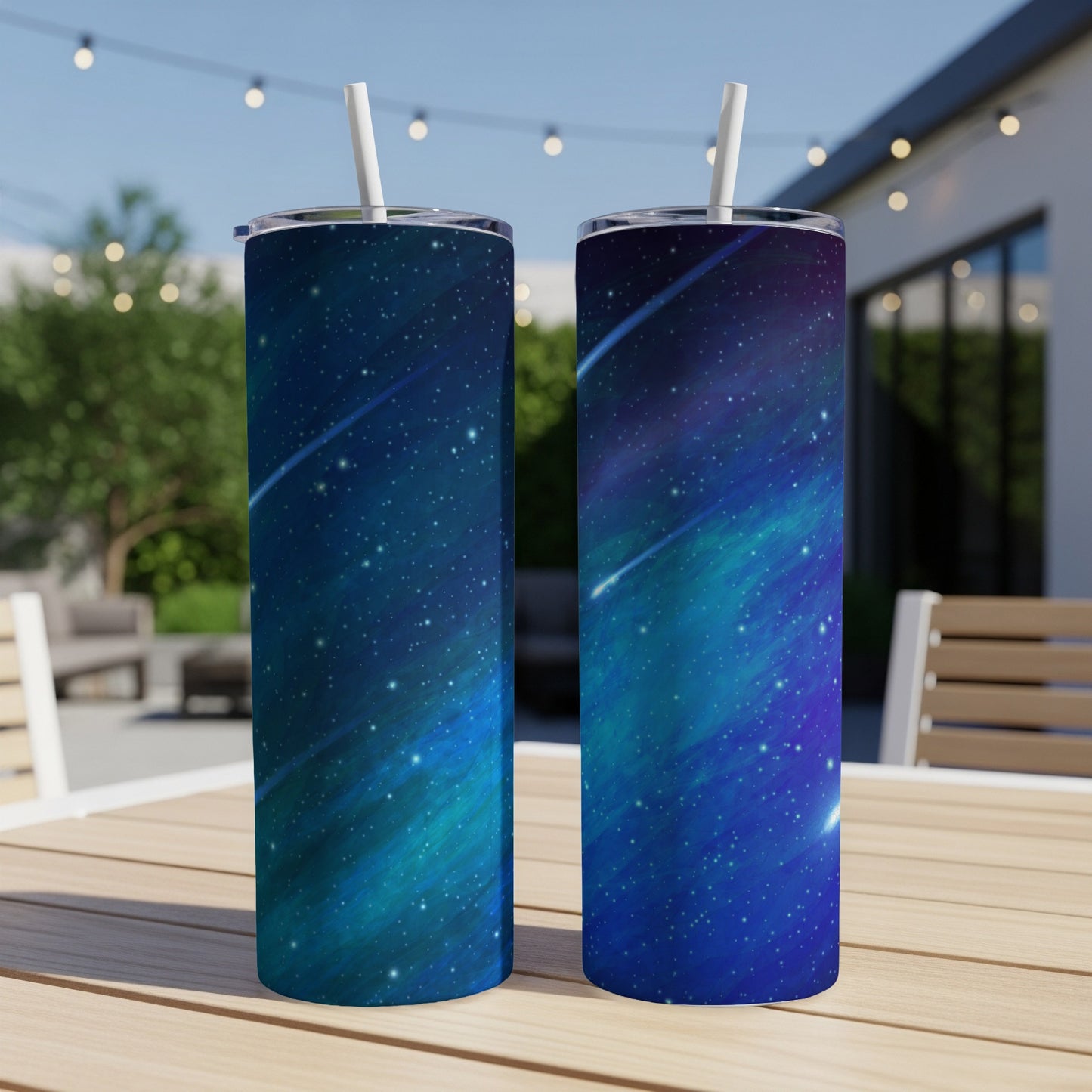 Two tumblers with a blue and teal starry nebula pattern and white straws.