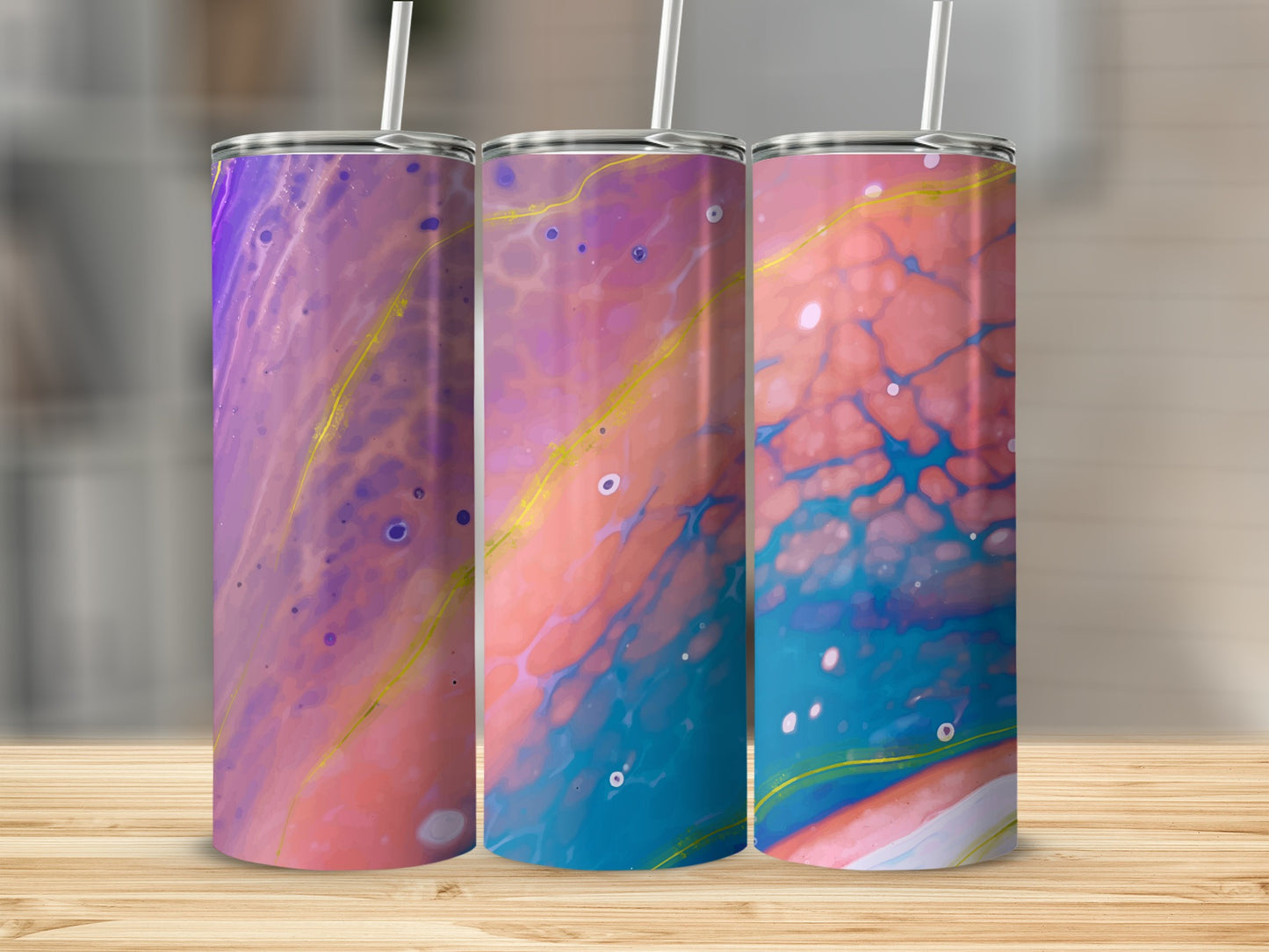 Three tumblers with colorful marbled patterns and gold accents stand on a wooden surface.