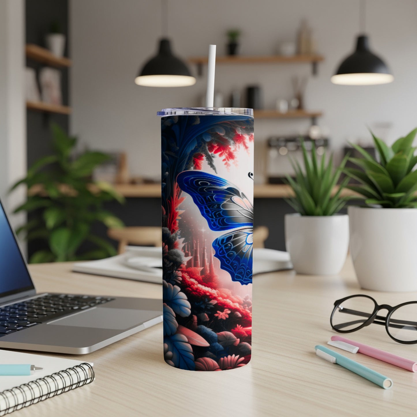 Tall insulated tumbler with blue butterfly and floral design on desk.