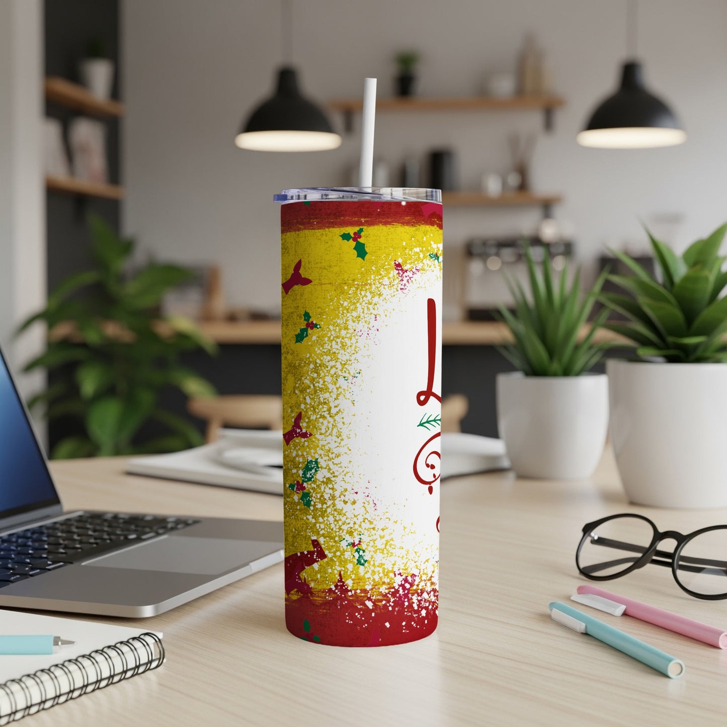 Red and yellow tumbler with white text and glitter accents on a desk.