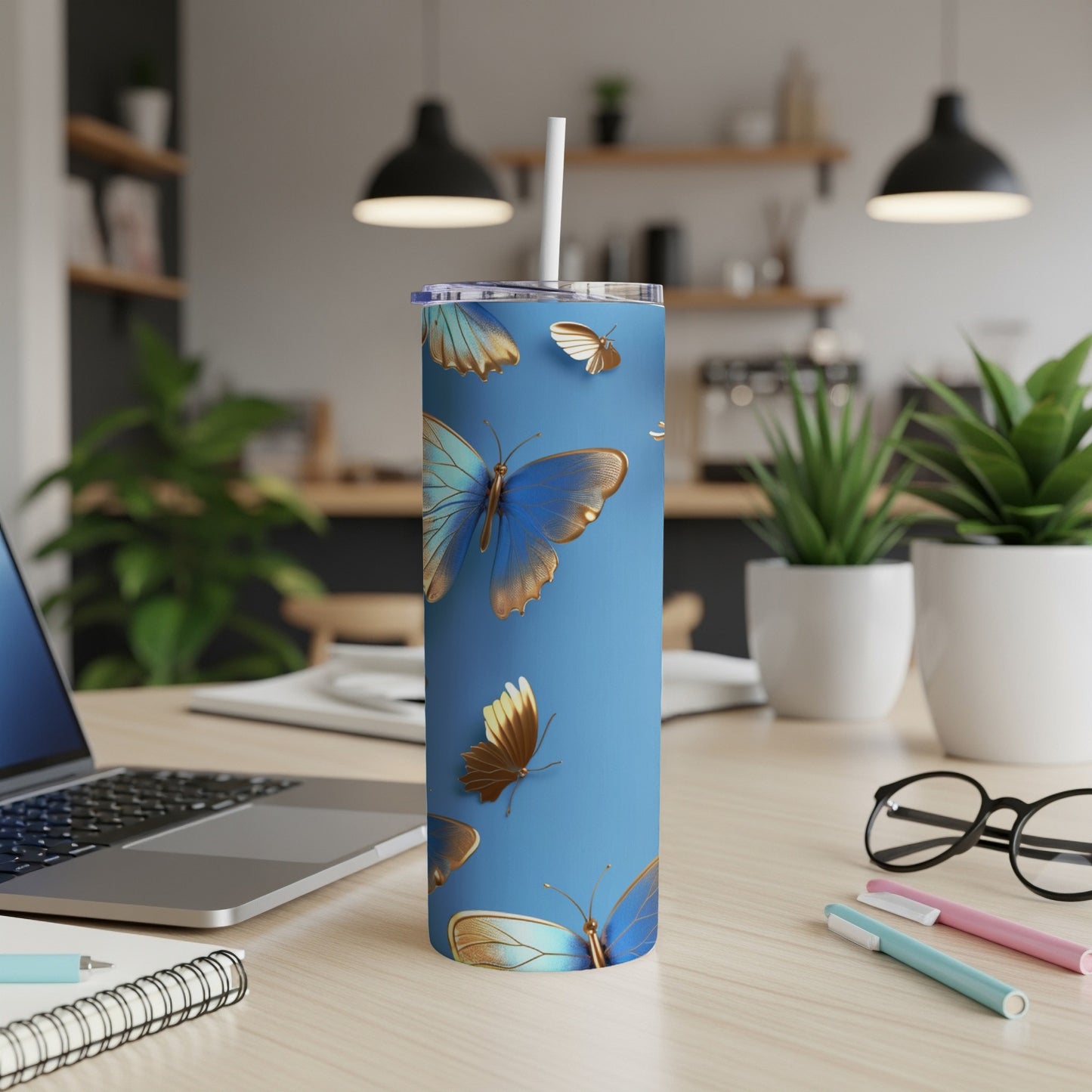 Blue tumbler with gold and blue butterflies, on a desk.