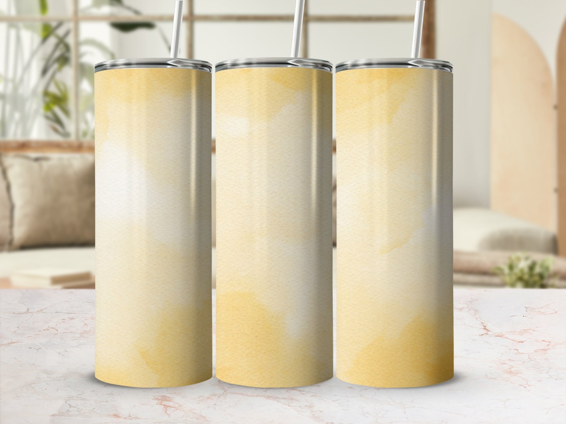 Three yellow watercolor gradient tumblers with straws on a marble surface.