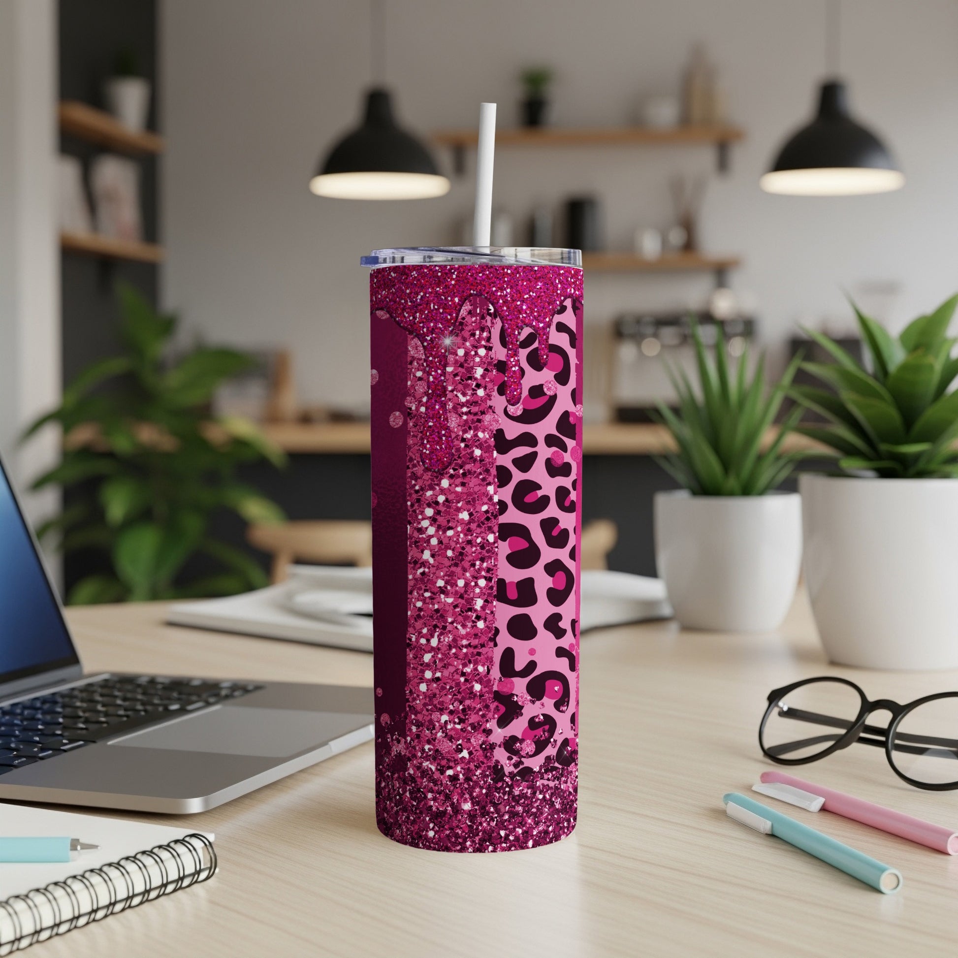 Pink glitter and leopard print tumbler with straw on a desk.