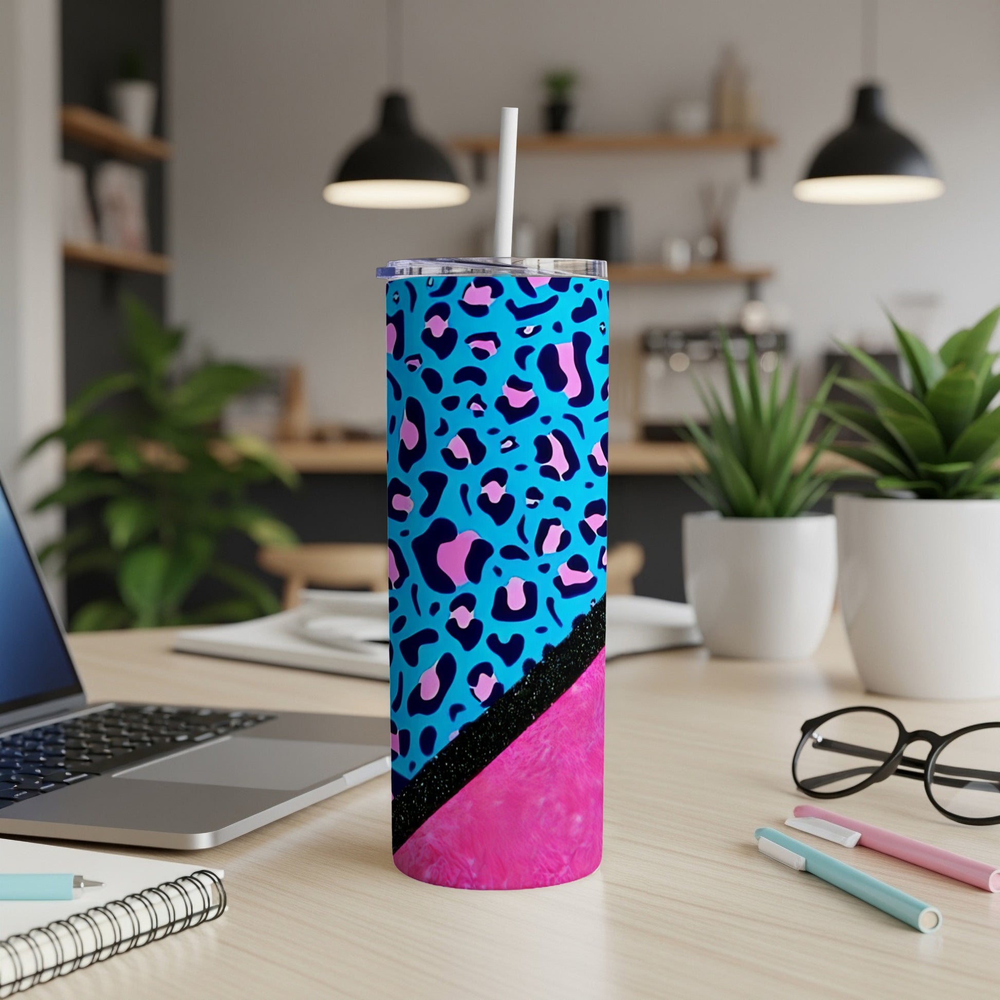 Blue tumbler with pink and black leopard print, on a desk.