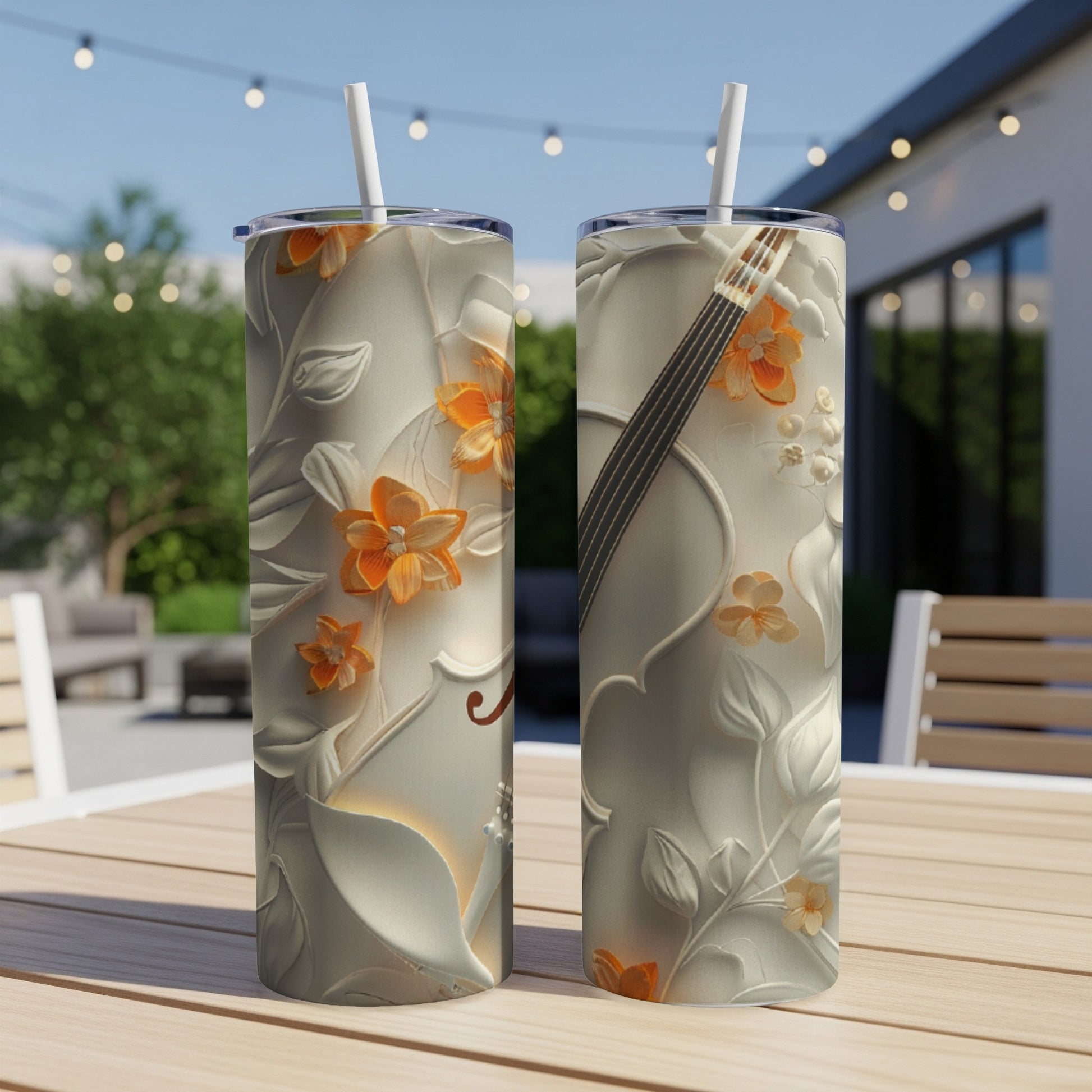 Two tumblers with embossed floral and violin designs on a patio table.
