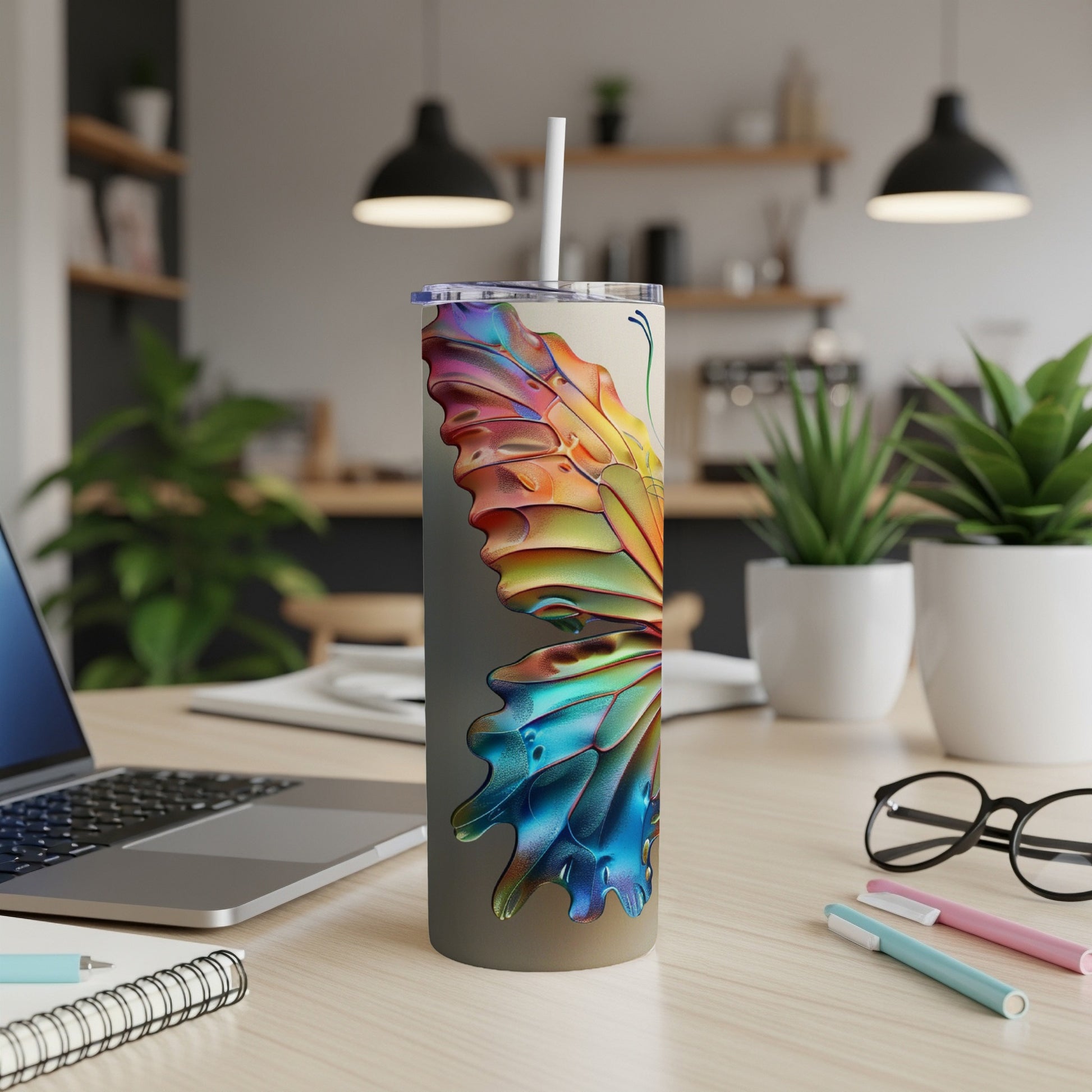 Colorful butterfly design on a skinny tumbler with a straw, on a desk.