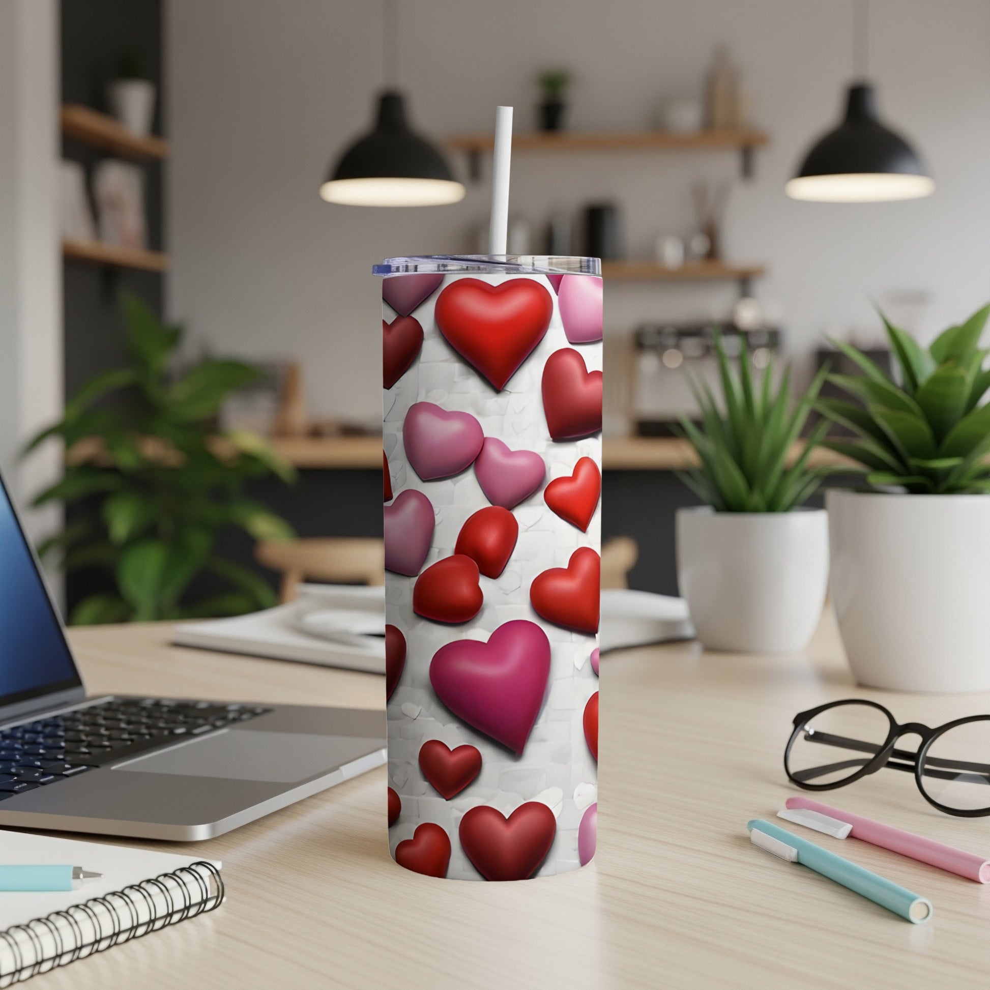 White tumbler with red and pink hearts, placed on a desk.