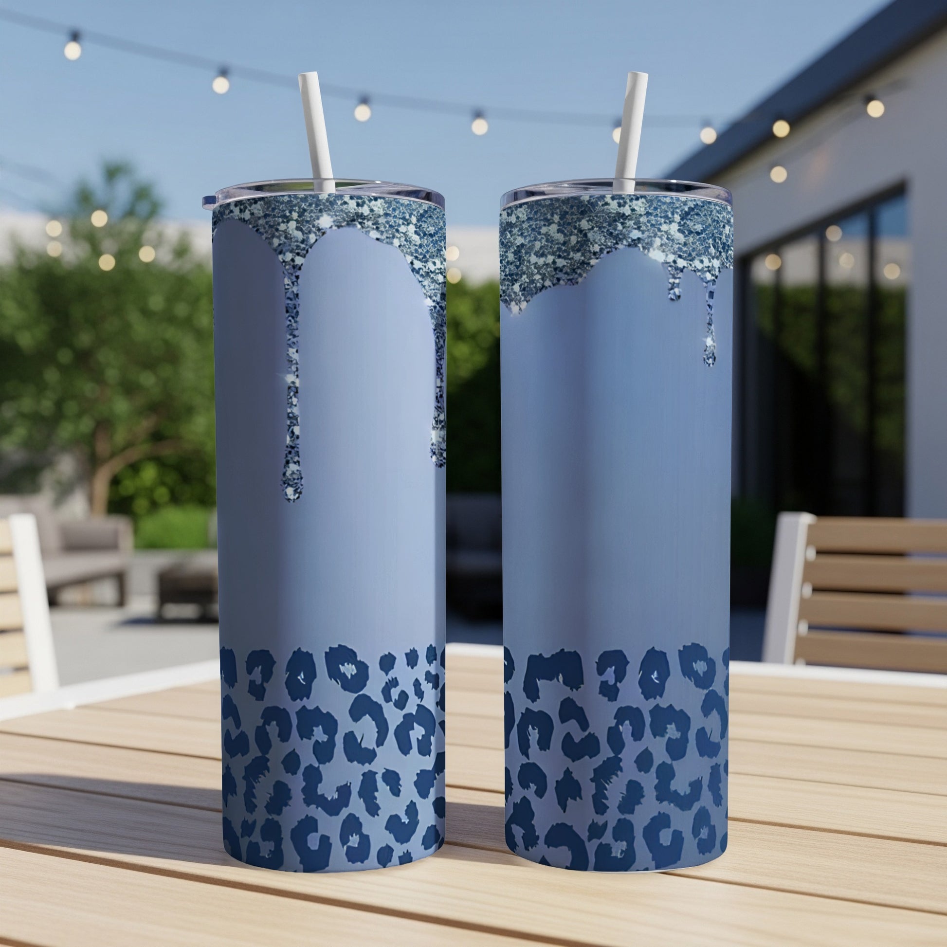 Two blue glitter drip tumblers with leopard print on a wooden table.