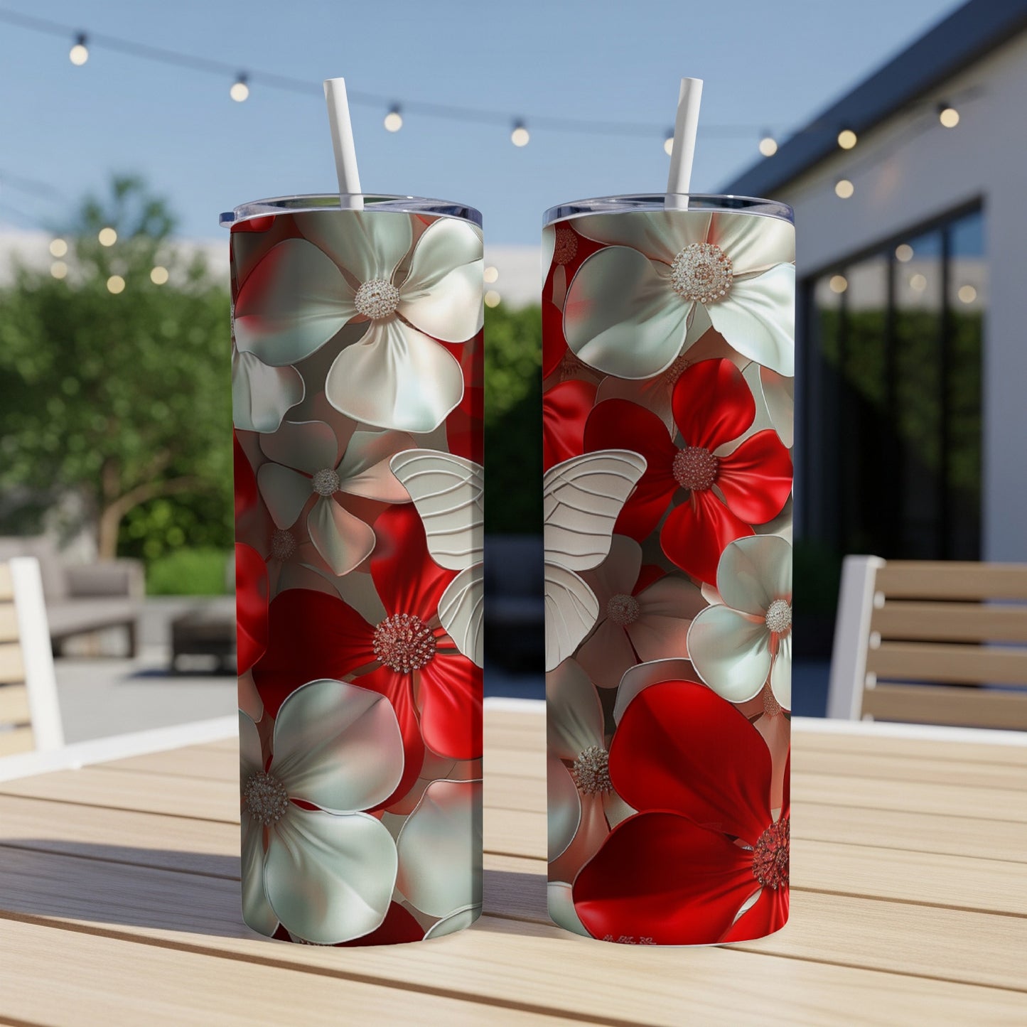 Two red and white floral patterned tumblers with straws on a wooden table.