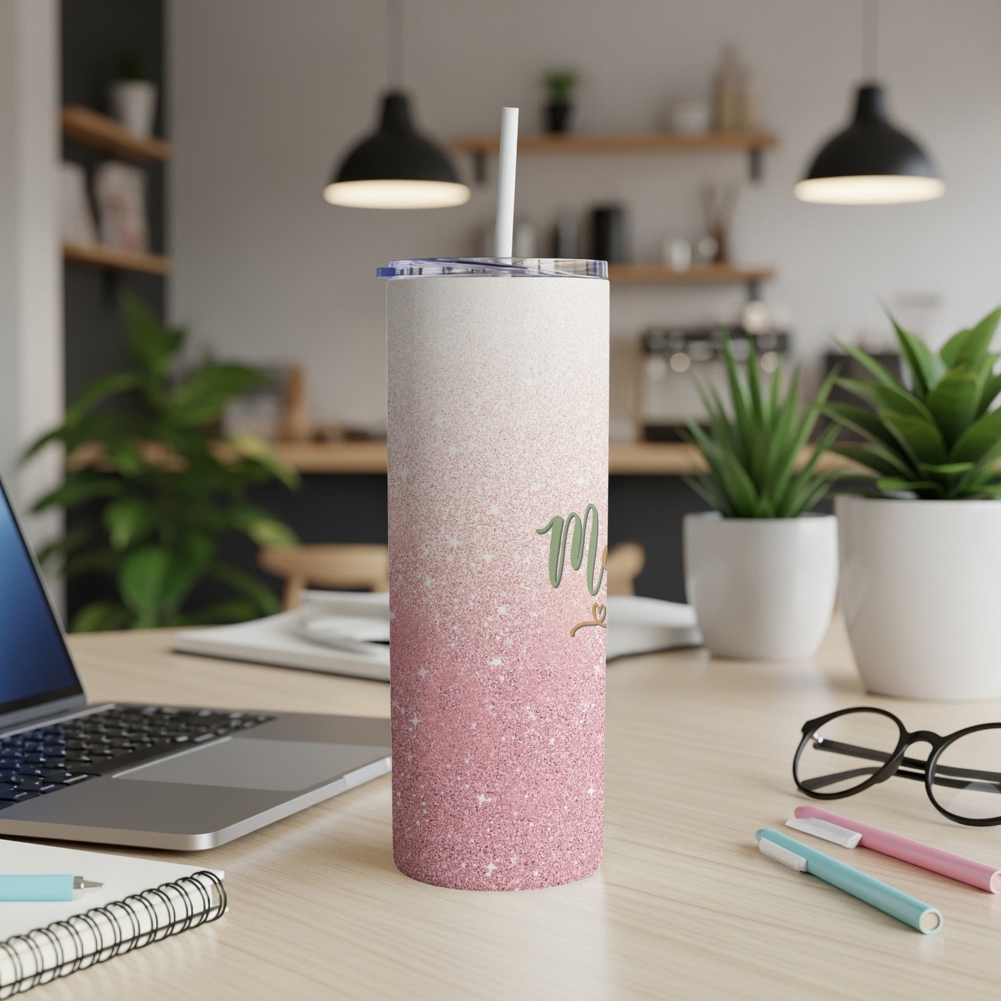 Glittery pink tumbler with "Mom" text and a straw on a desk.