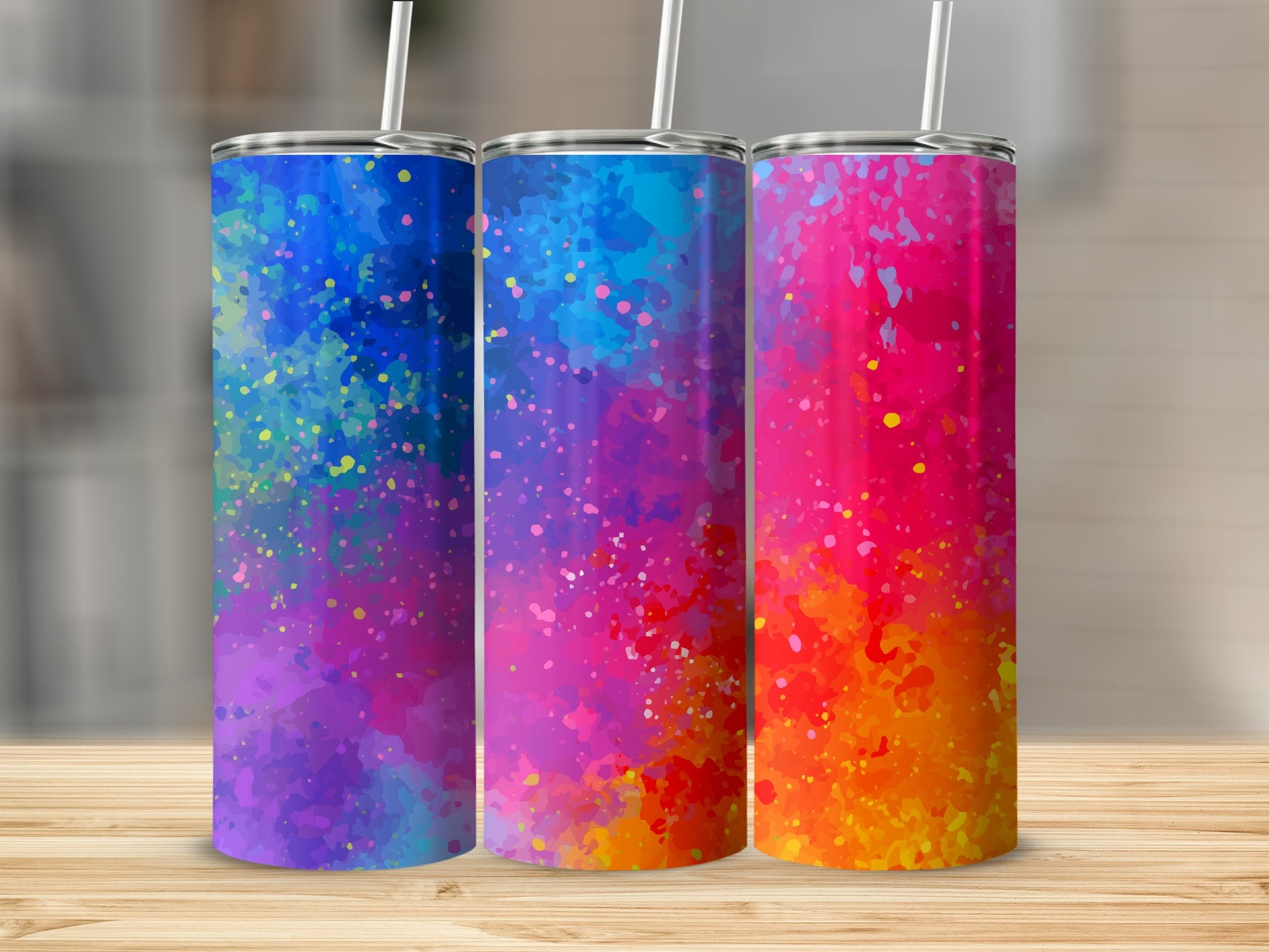 Three tumblers with colorful splatter paint designs in purple, blue, and pink.