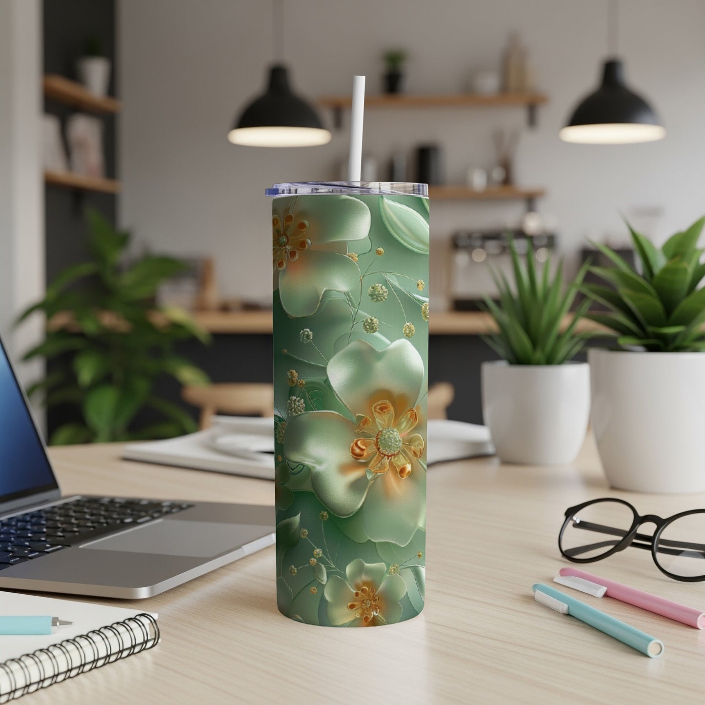 Green floral patterned tumbler with straw on desk.