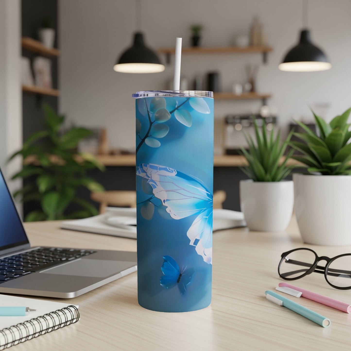 Blue tumbler with butterfly design, white straw, on a desk.