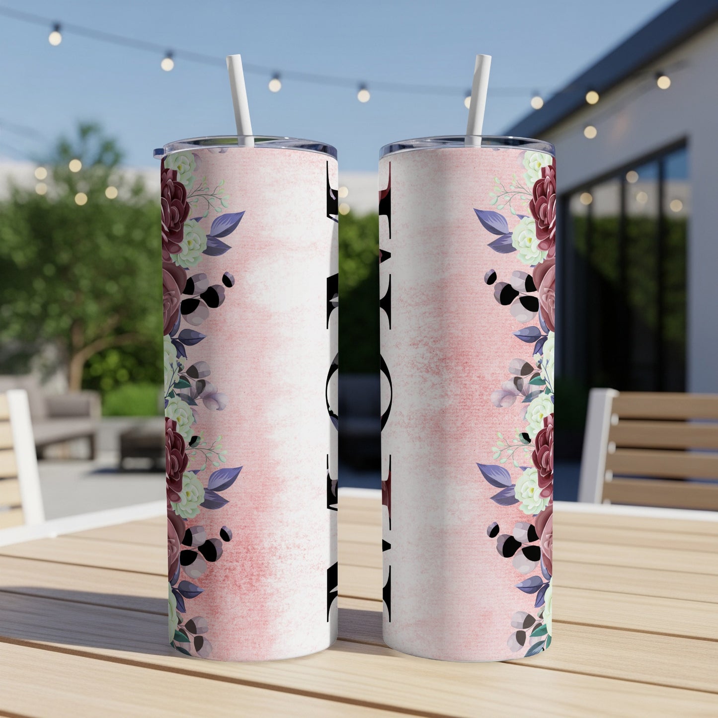 Two tumblers with floral design and text, on a wooden table outdoors.