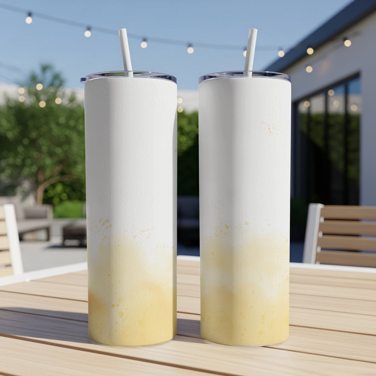 Two white tumblers with yellow speckled design on a table.