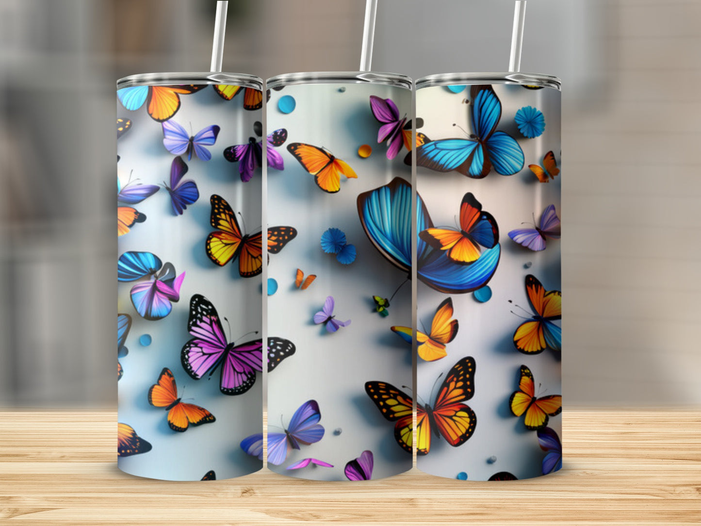 Three tumblers with colorful butterfly designs on a wooden surface.