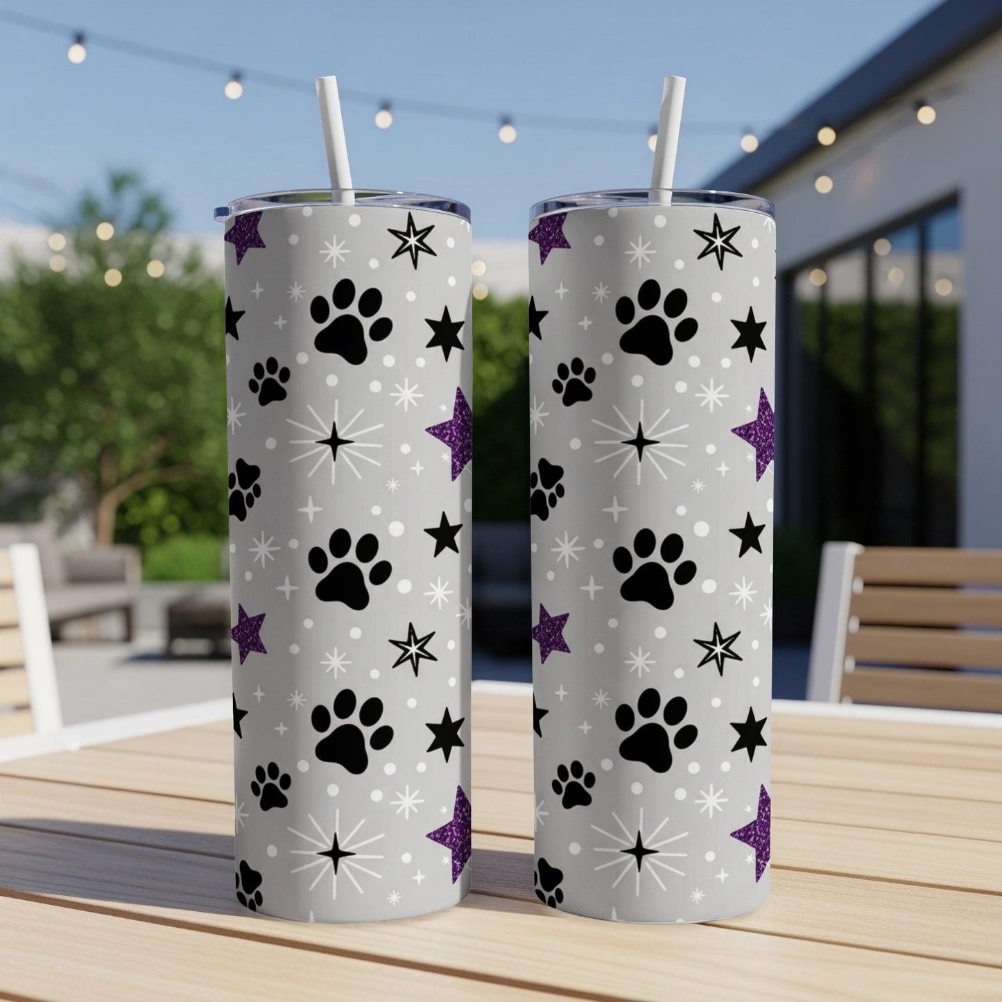Two tall, silver tumblers with paw prints, stars, and purple glitter.