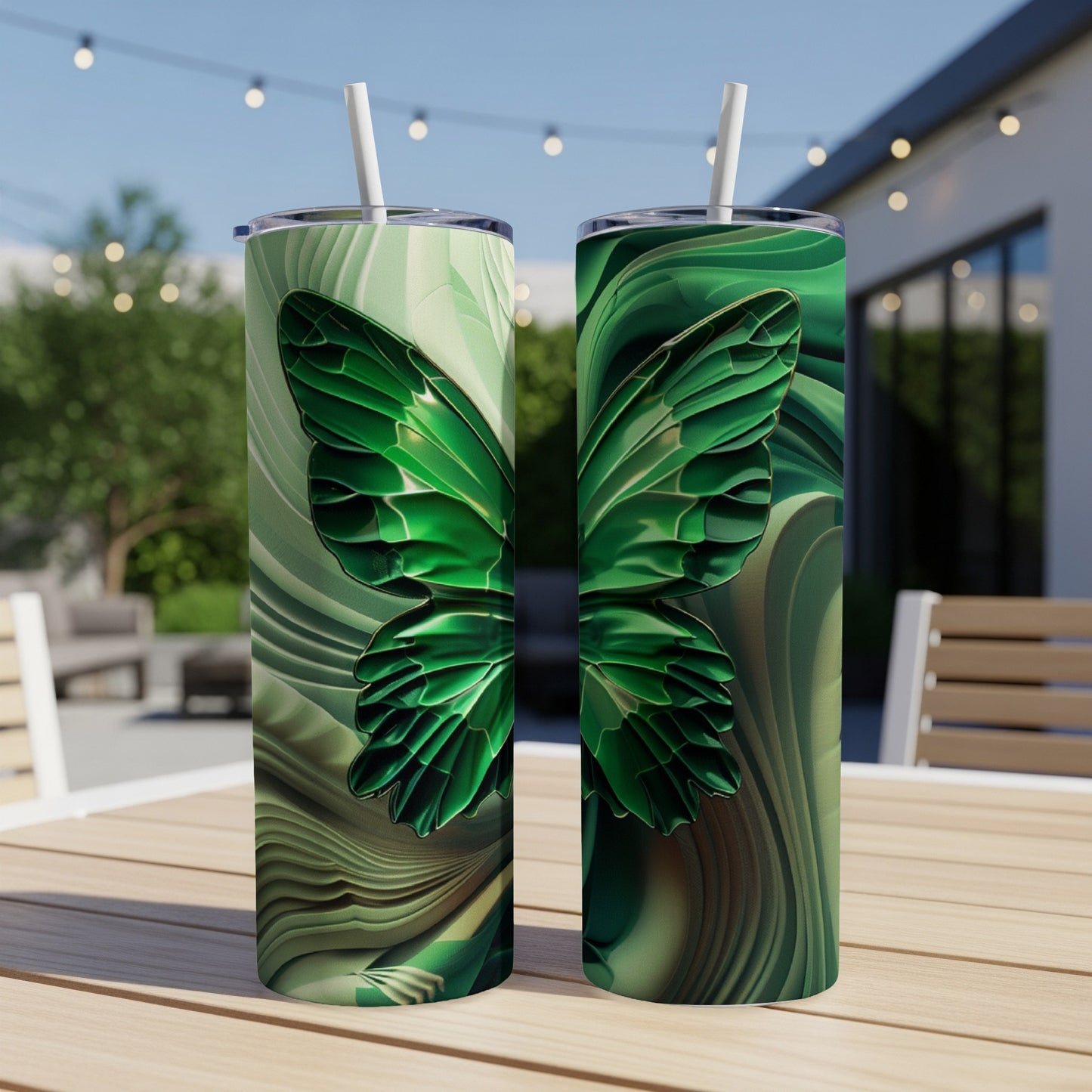 Green butterfly design on two tumblers with straws on a table.